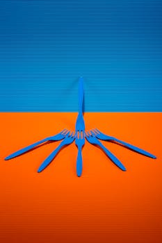 Artistic arrangement of blue forks on an orange surface with a blue backdrop creates a vivid contrast.