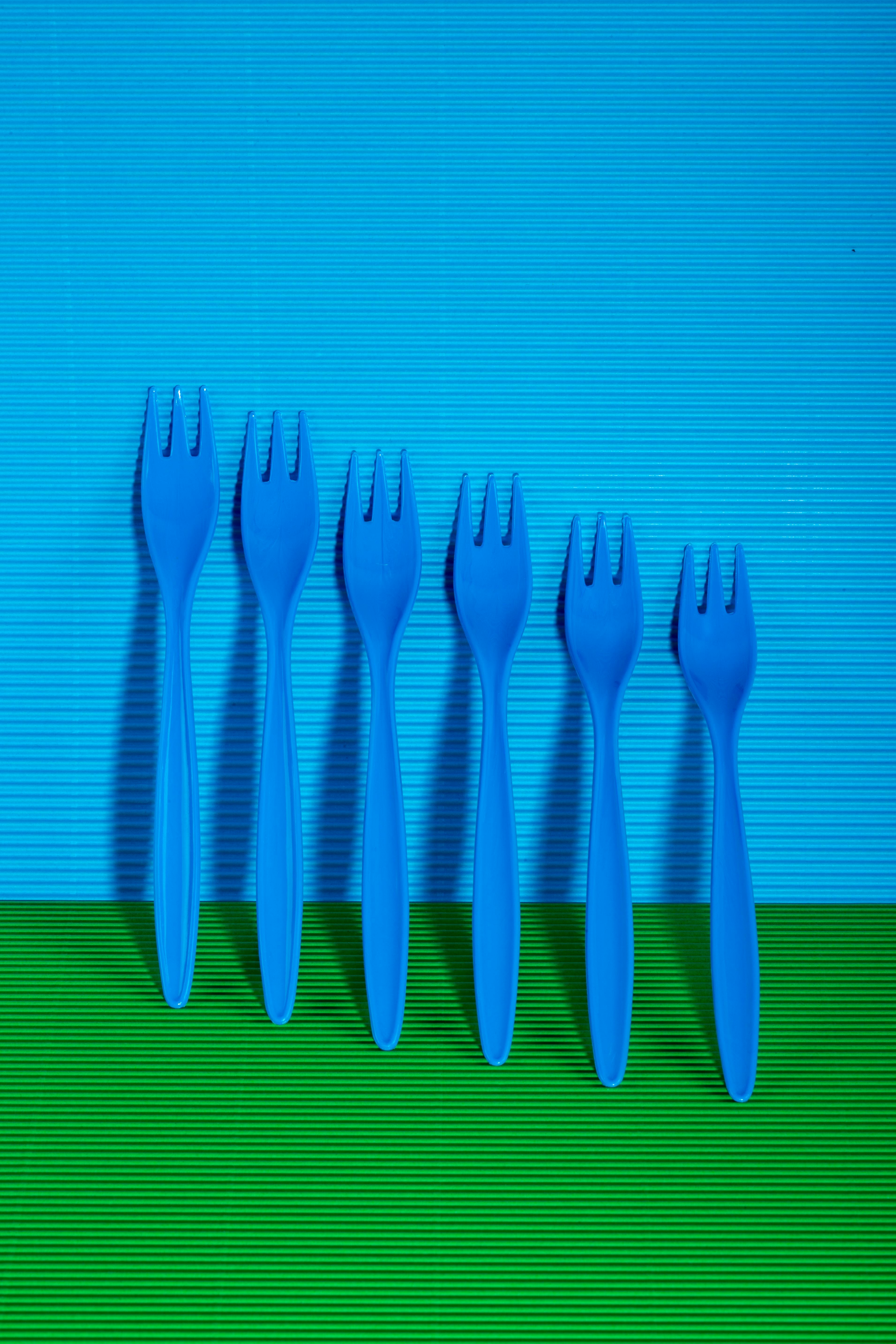Ücretsiz Canlı yeşil ve mavi bir arka plan üzerinde altı adet mavi plastik çatal. Stok Fotoğraflar