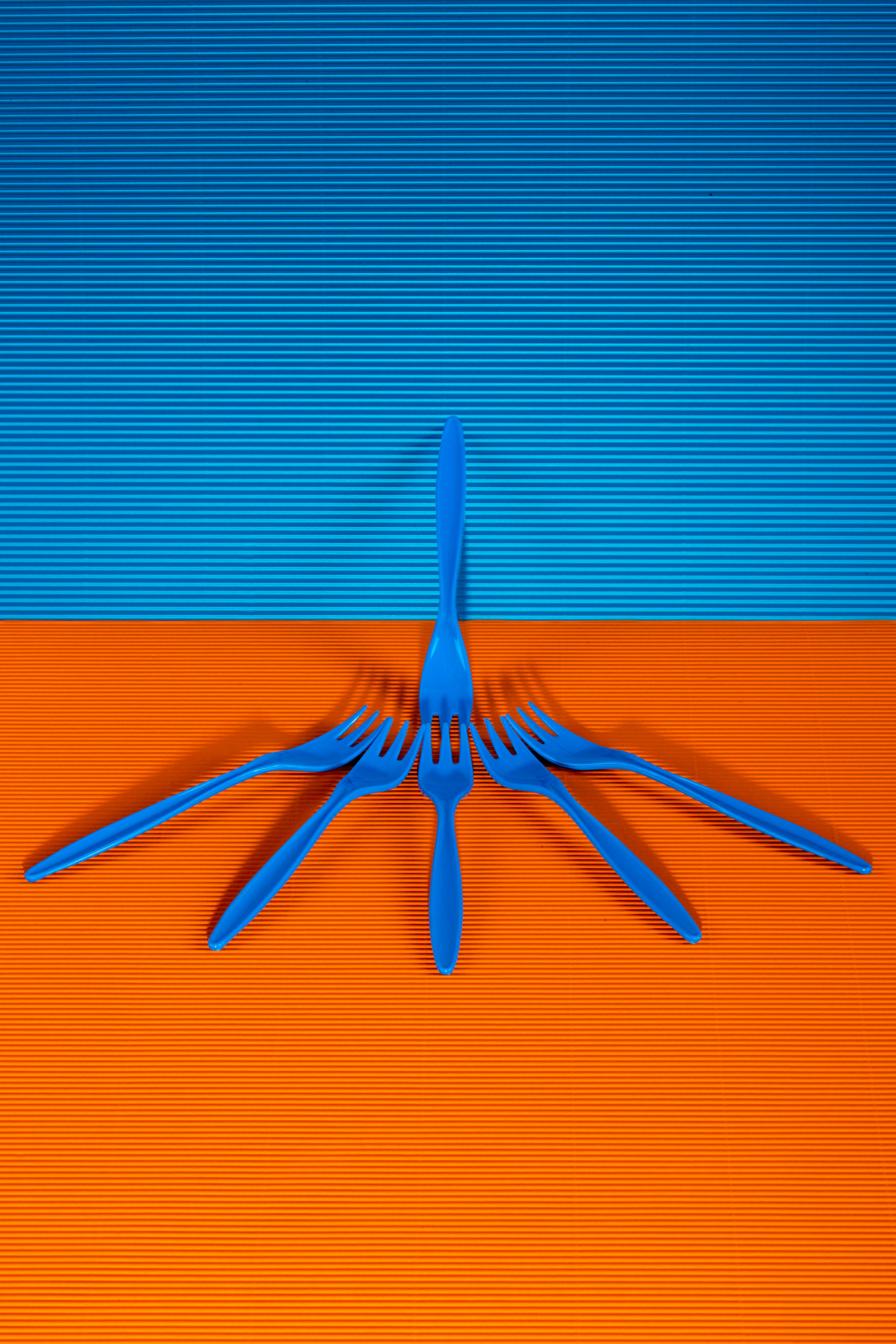 Free Striking image of blue forks artistically arranged on a vivid blue and orange backdrop. Stock Photo
