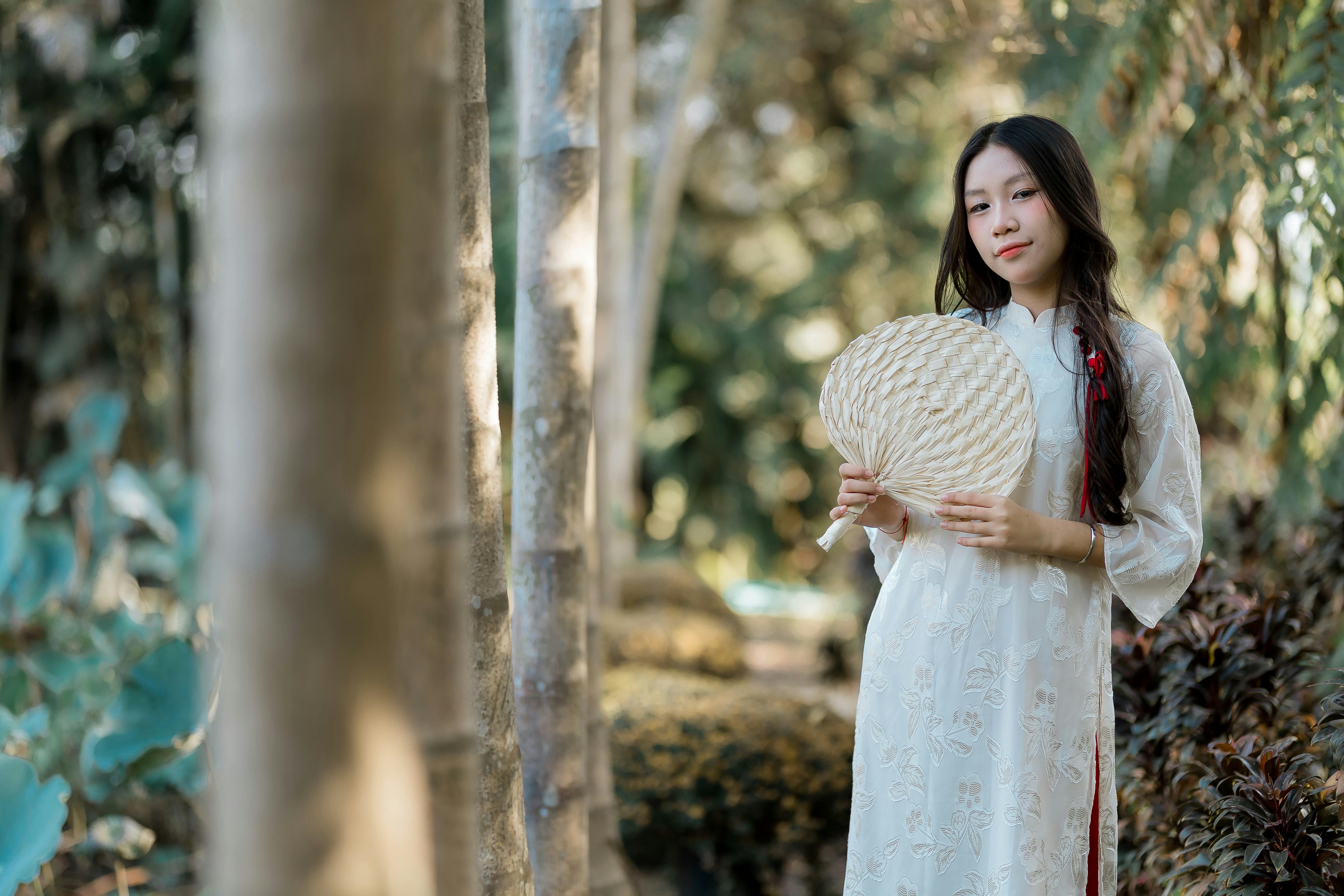 ingyenes Egy fiatal nő hagyományos viseletben, legyezőt tartva, természet ölelésében. Stockfotó