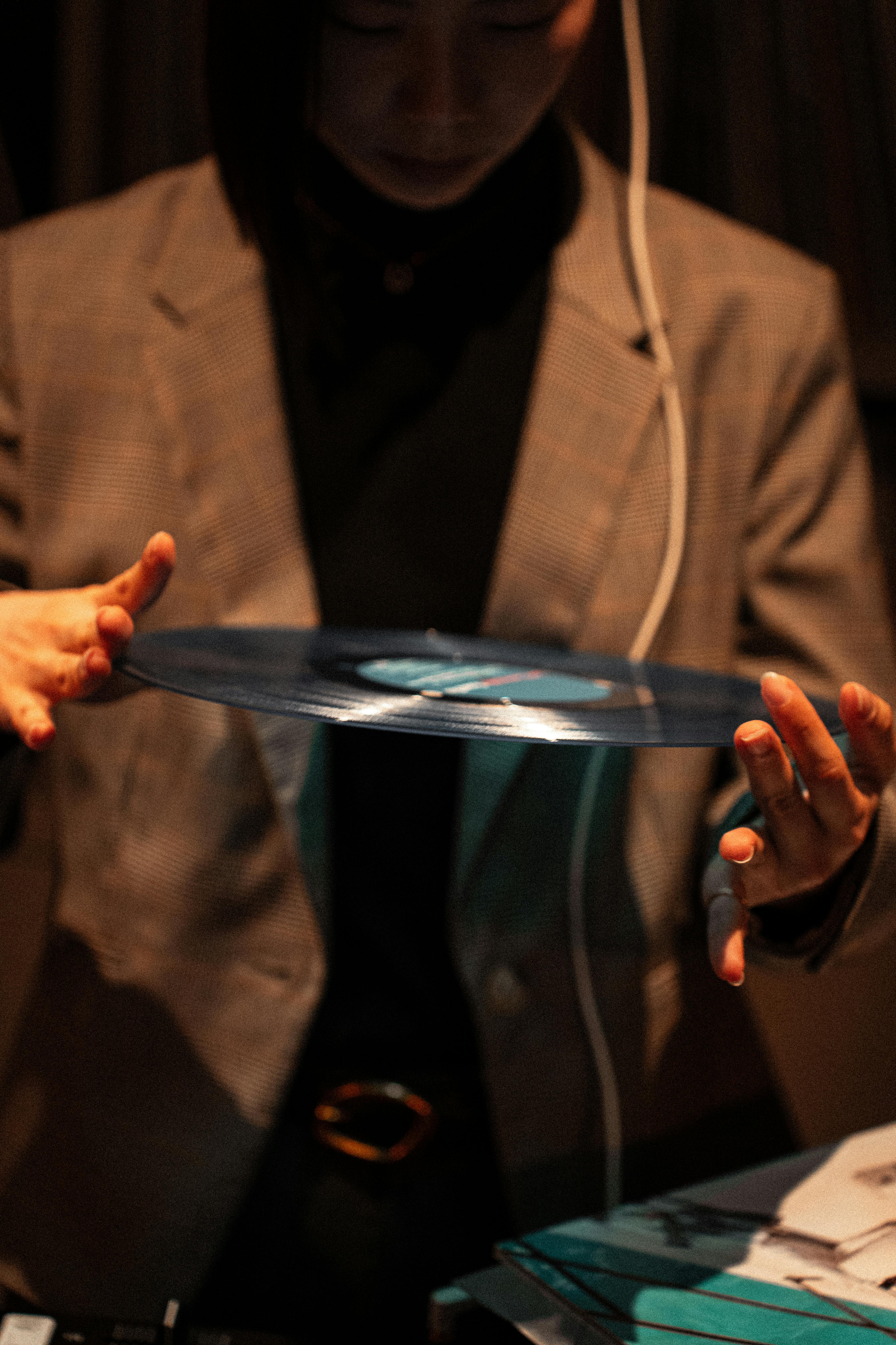 Miễn phí Một DJ cầm một đĩa than màu xanh lam trong không gian ánh sáng mờ ảo, tạo nên bầu không khí âm nhạc cổ điển. Ảnh lưu trữ