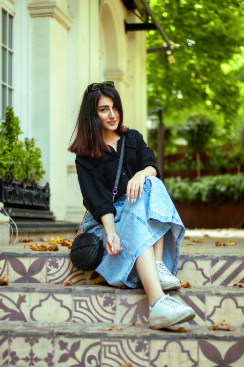 Free Young woman sitting on decorative steps outdoors, enjoying a quiet moment surrounded by greenery. Stock Photo