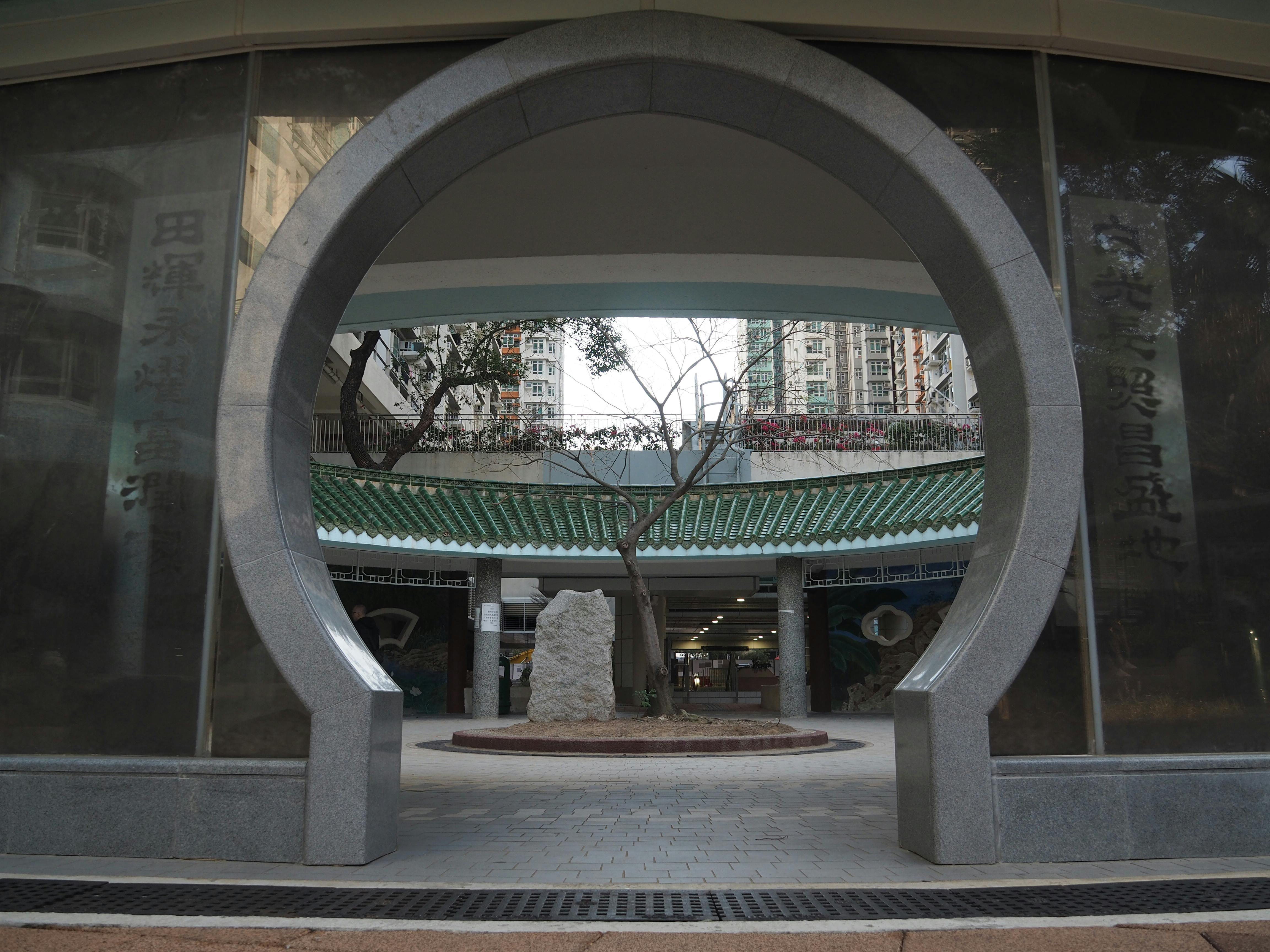 Gratis Måneporten som fører til en rolig urban gårdsplass med grønne tak og moderne bygninger i Hong Kong. Arkivbilde