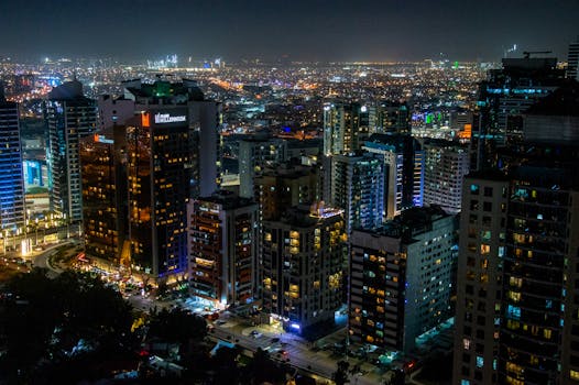 Stunning aerial view of a bustling city skyline illuminated at night, showcasing modern skyscrapers and dynamic city life.
