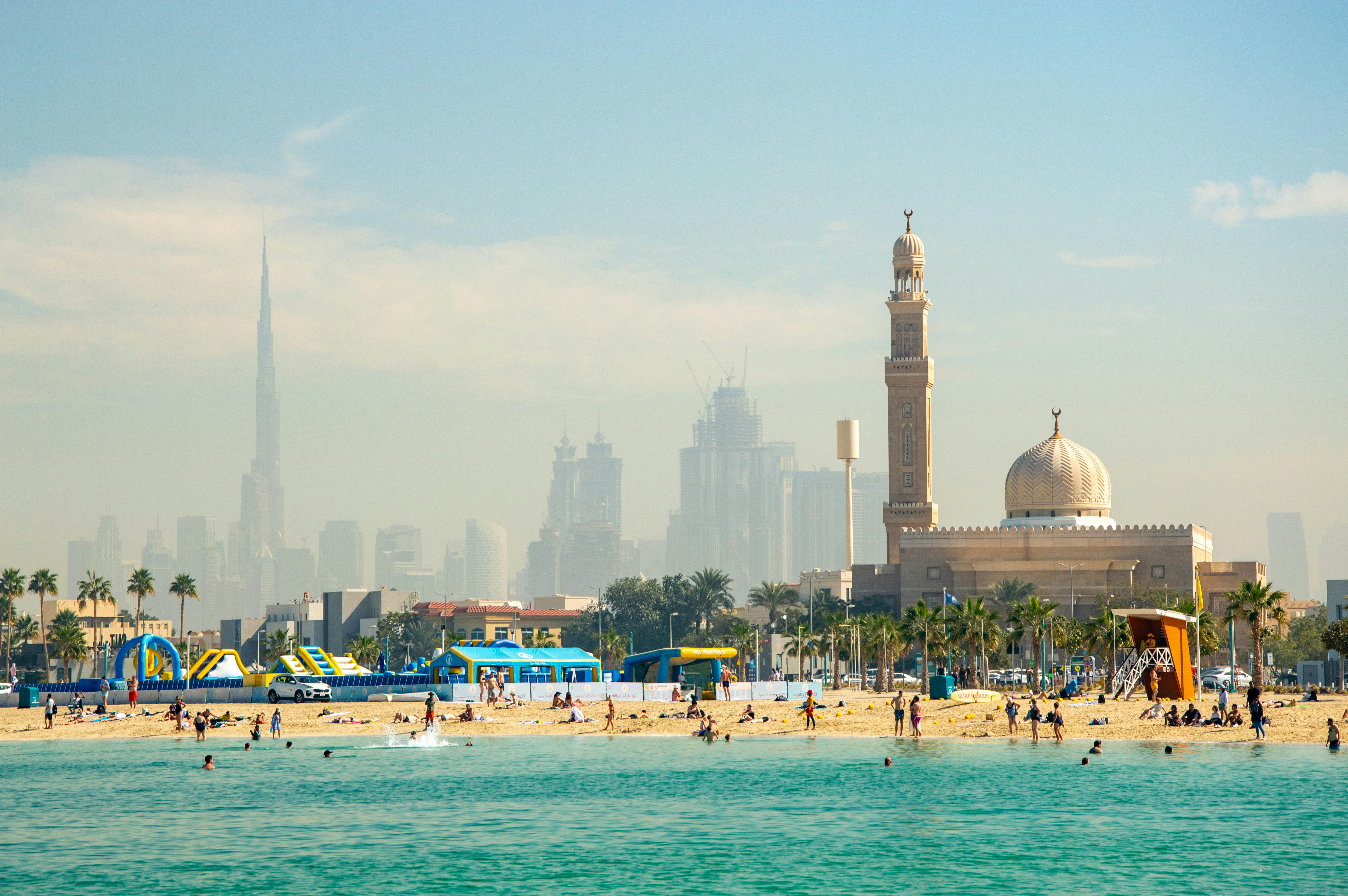 A vibrant beach scene with Dubai's iconic skyline, featuring Burj Khalifa and Al Farooq Mosque.