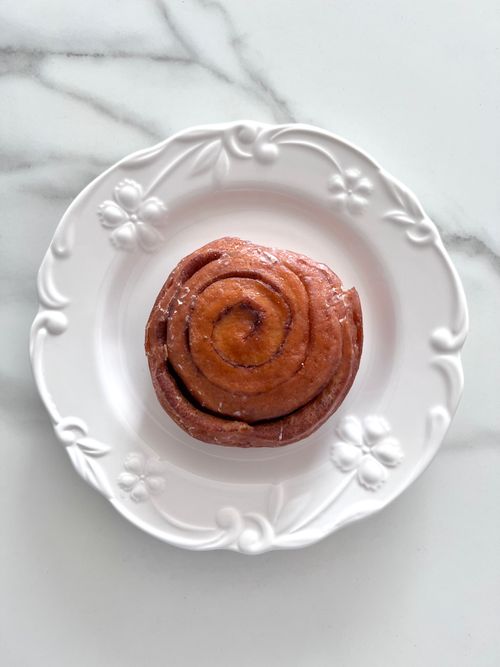Free Freshly baked cinnamon roll on an ornate ceramic plate, perfect for breakfast. Stock Photo
