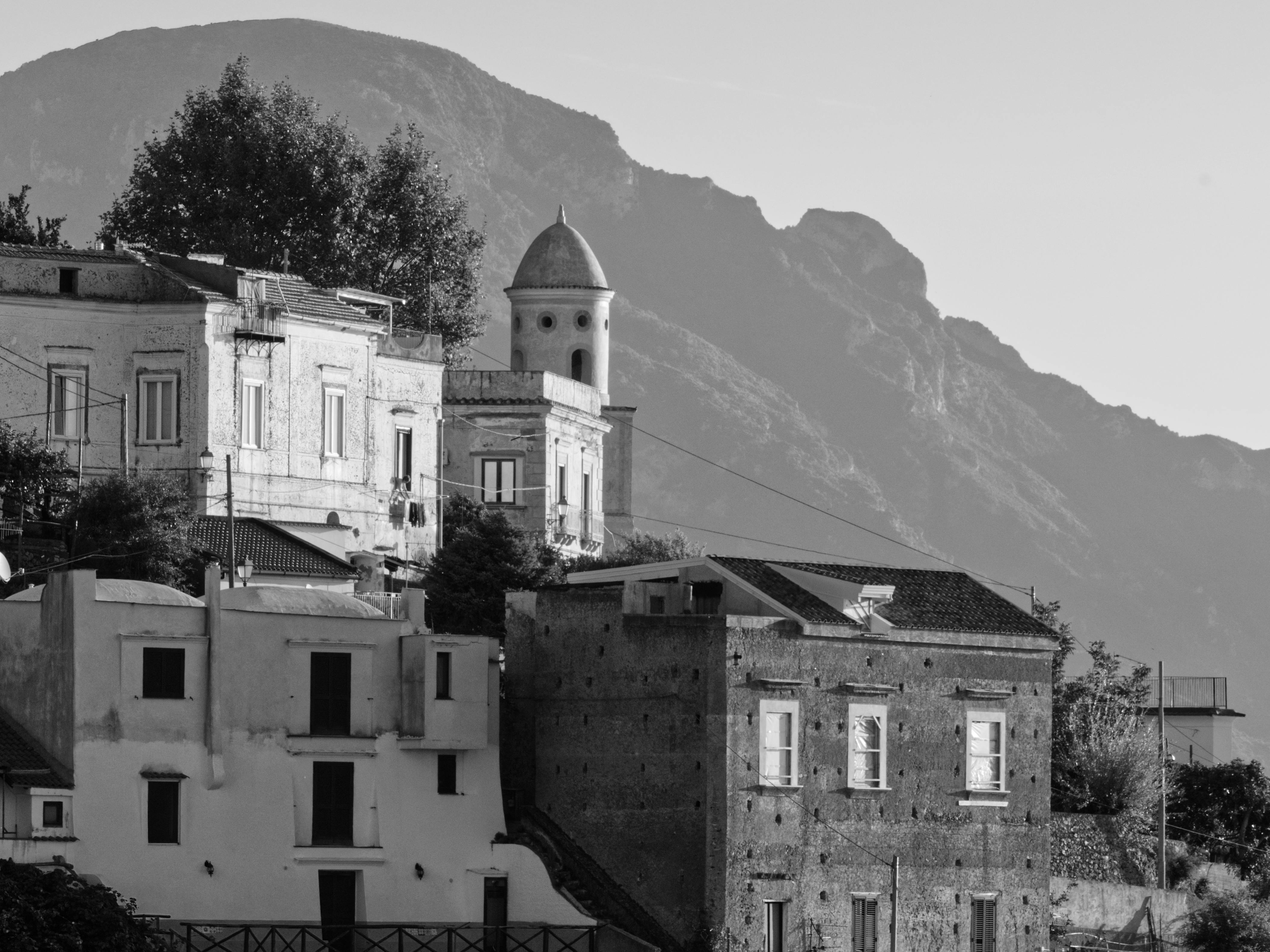 Δωρεάν Ασπρόμαυρη φωτογραφία ρουστίκ ιταλικών κτιρίων με βουνά στο φόντο, που αποπνέει μια διαχρονική γοητεία. Φωτογραφία από στοκ φωτογραφιών