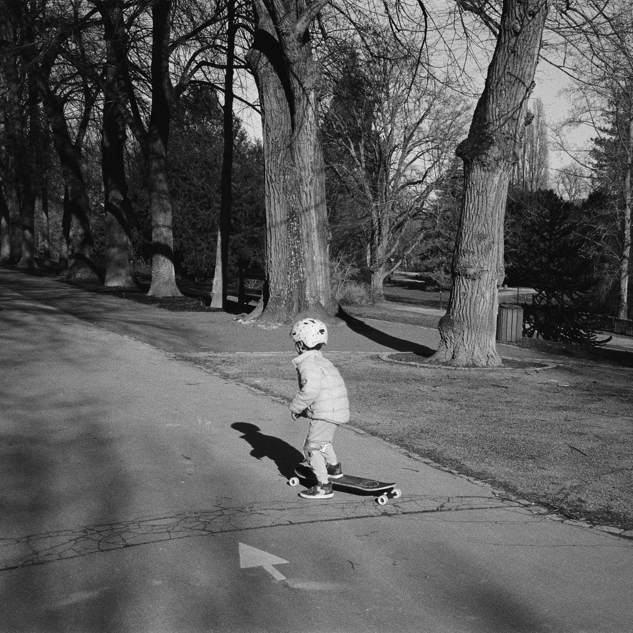 Δωρεάν Ένα παιδί που φοράει κράνος απολαμβάνει να κάνει σκέιτμπορντ σε ένα ηλιόλουστο πάρκο. Φωτογραφία από στοκ φωτογραφιών