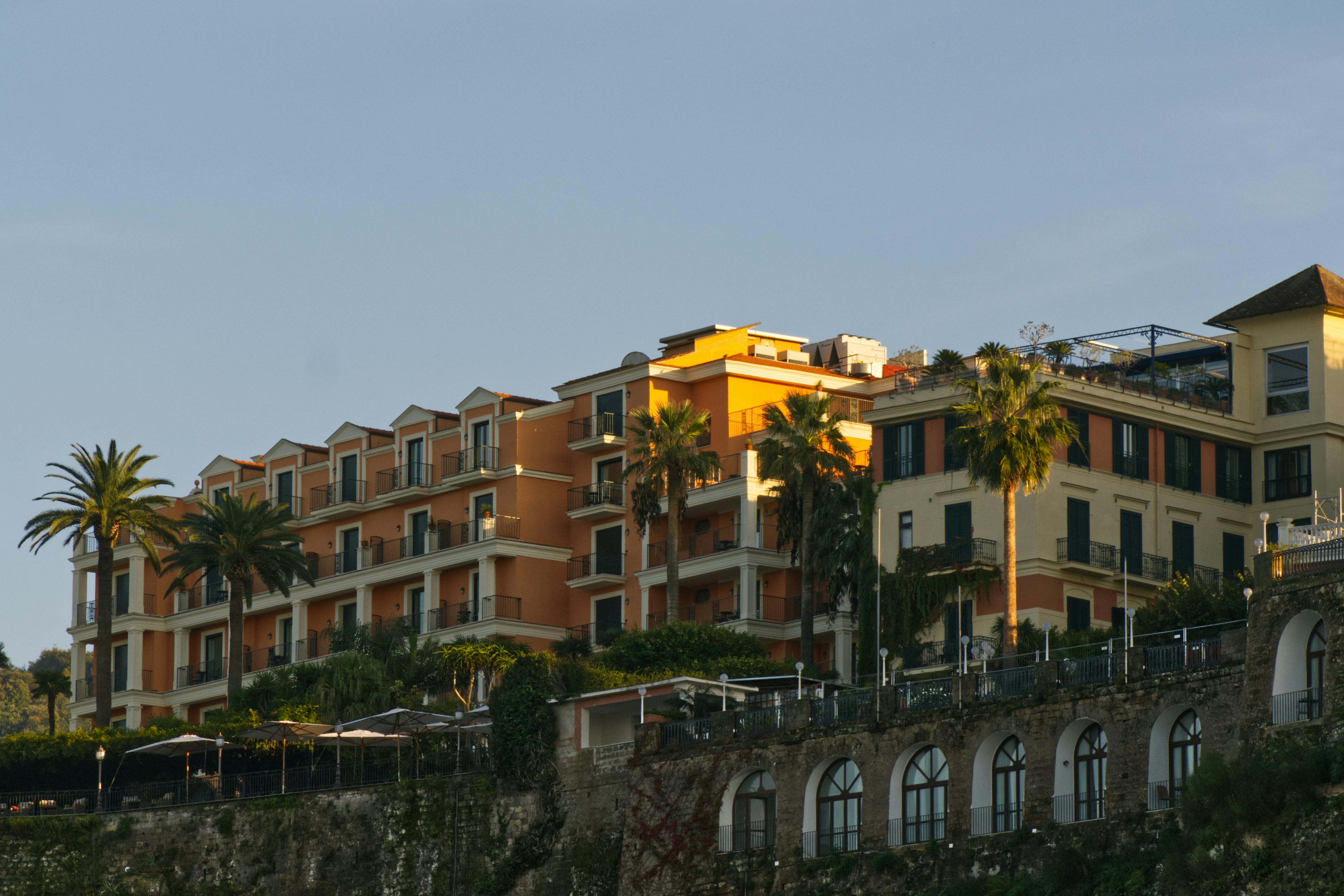 Δωρεάν Γοητευτικό μεσογειακό ξενοδοχείο με φοίνικες στο ηλιοβασίλεμα, που αναδεικνύει την παραδοσιακή αρχιτεκτονική και τη γαλήνια ατμόσφαιρα. Φωτογραφία από στοκ φωτογραφιών