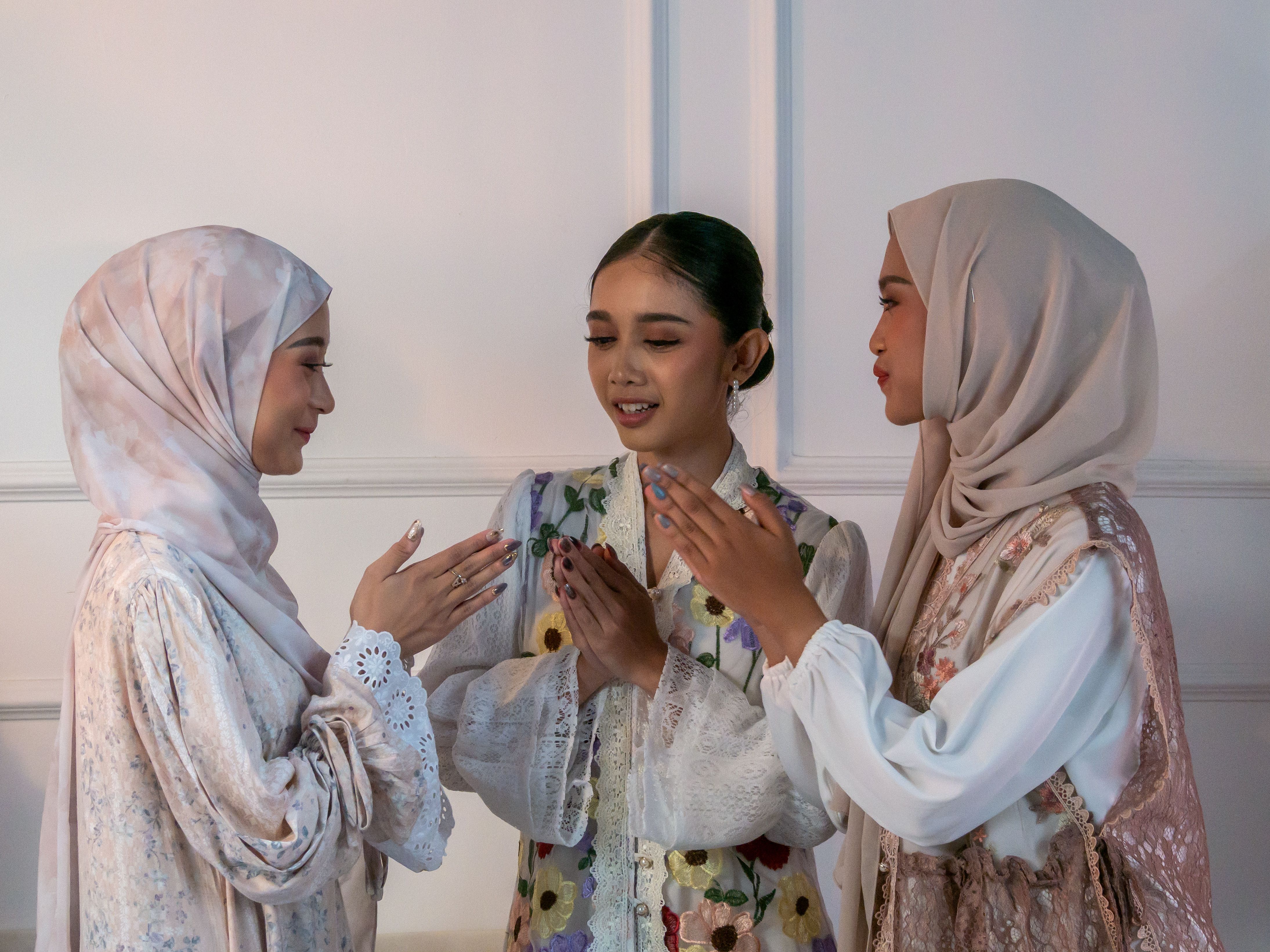 Three women in festive traditional attire celebrate joyfully indoors, expressing happiness and connection.