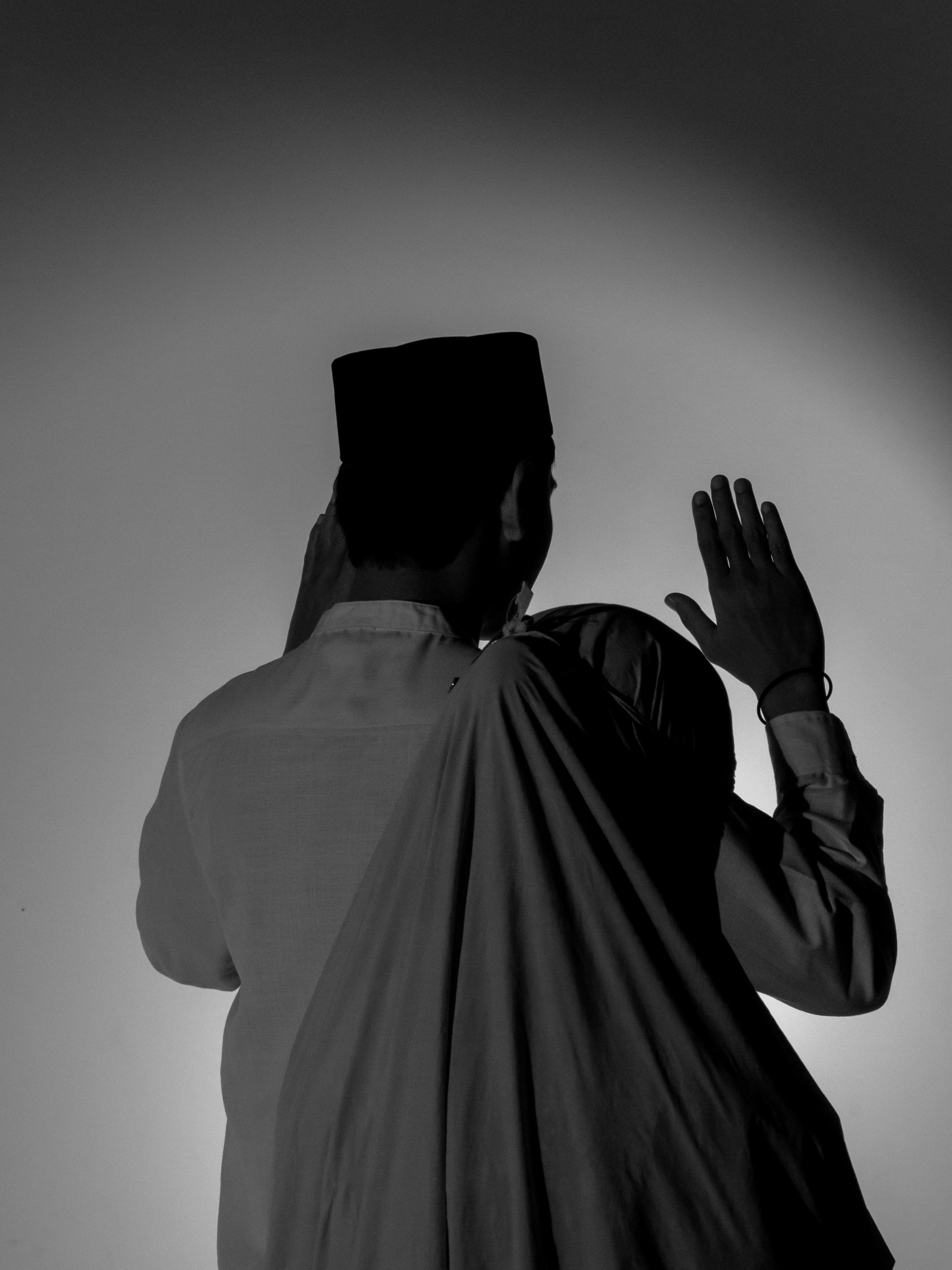 Free Black and white silhouette of two individuals in a prayer position, creating a spiritual ambiance. Stock Photo