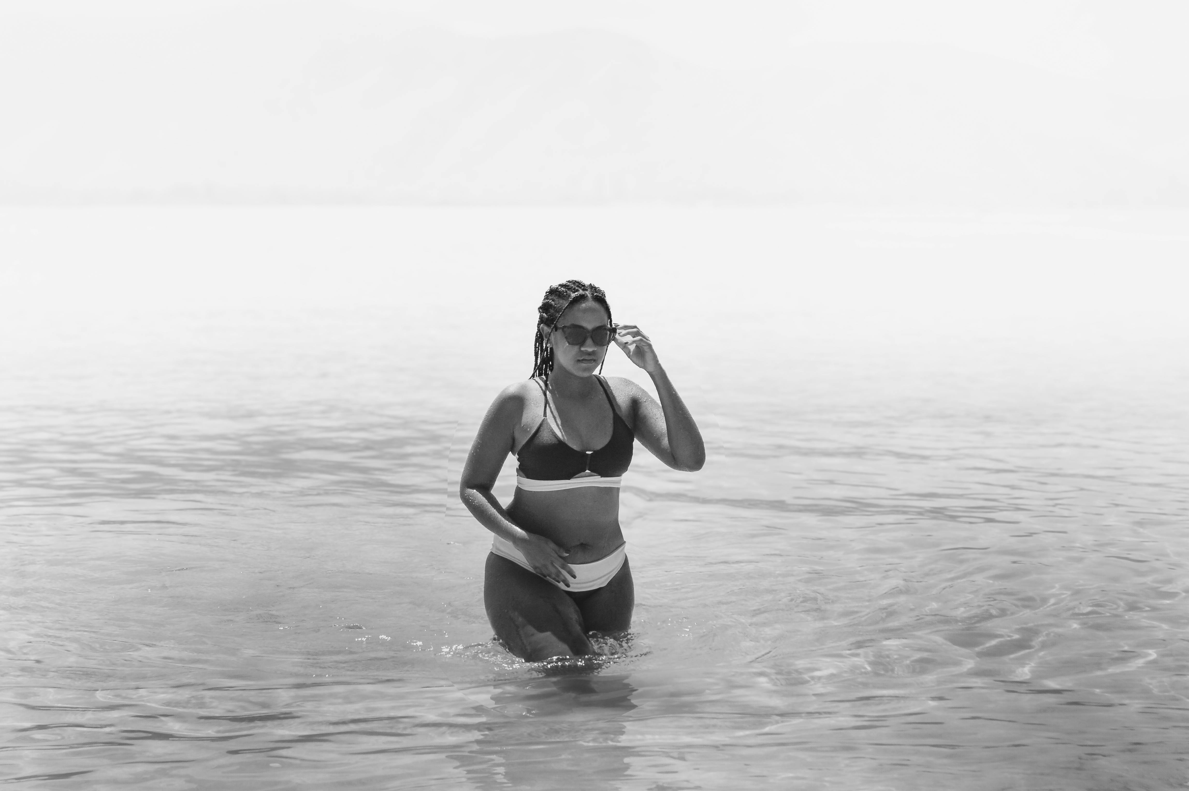 Δωρεάν Μια γυναίκα περπατάει μέσα από ρηχά νερά του ωκεανού σε μια ασπρόμαυρη φωτογραφία. Φωτογραφία από στοκ φωτογραφιών