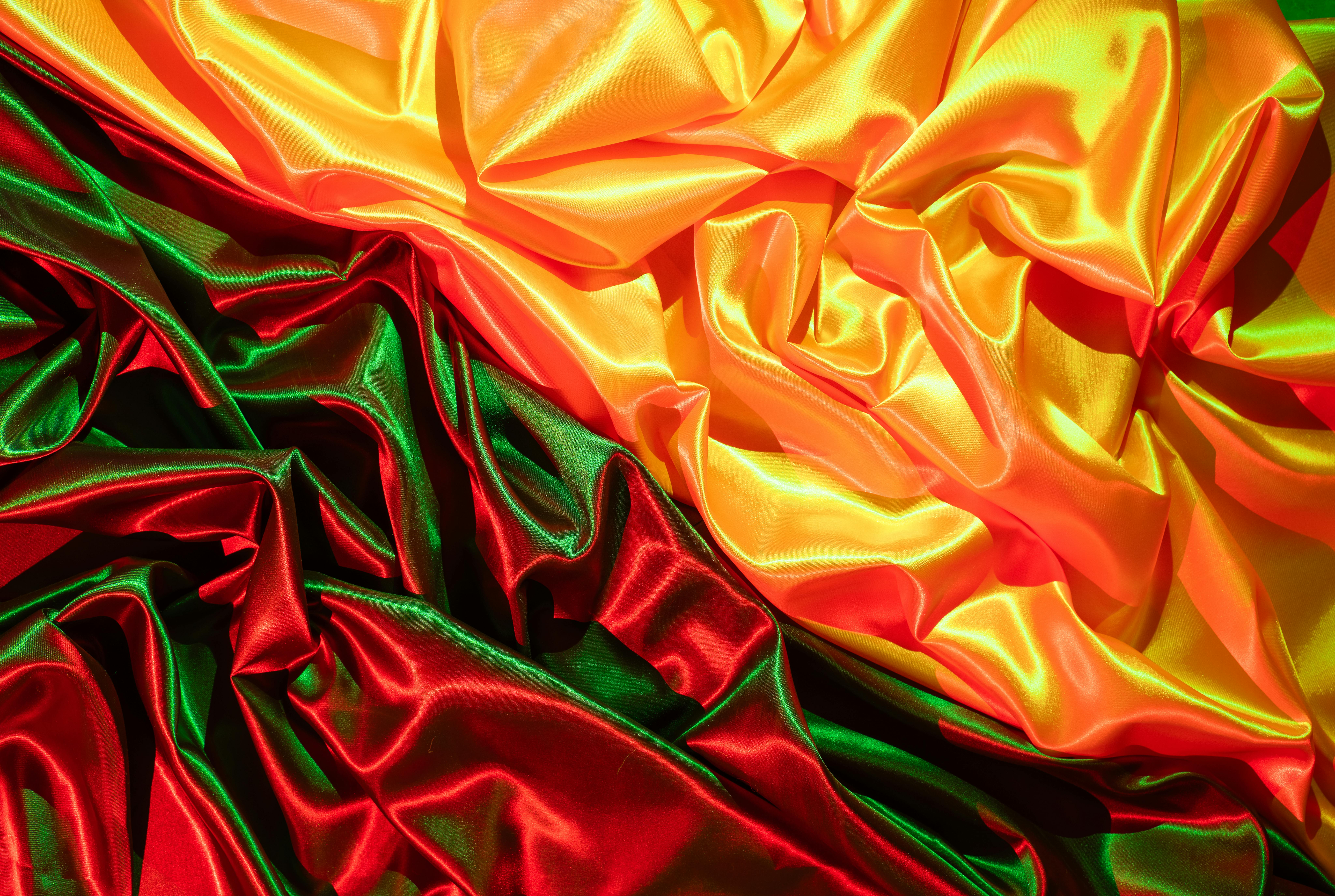 Δωρεάν Μια ζωντανή απεικόνιση τσαλακωμένου σατέν υφάσματος σε κόκκινες και κίτρινες αποχρώσεις, που δημιουργεί μια πολυτελή υφή. Φωτογραφία από στοκ φωτογραφιών