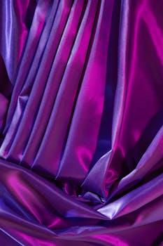 Close-up of vibrant, colorful silk fabric with luxurious folds and glossy texture.