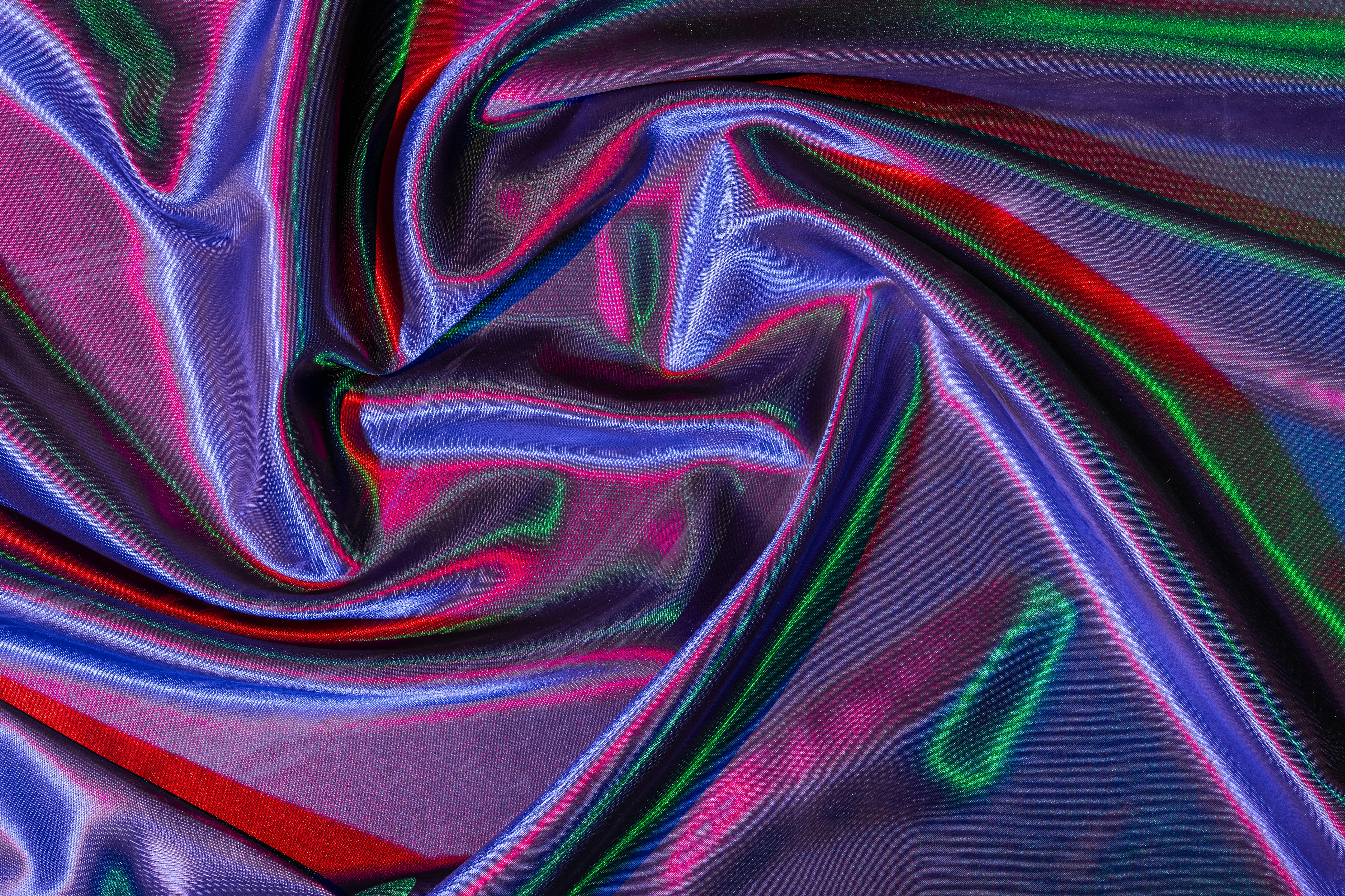 Free A vibrant and colorful iridescent satin fabric with flowing folds. Perfect for artistic and decorative designs. Stock Photo