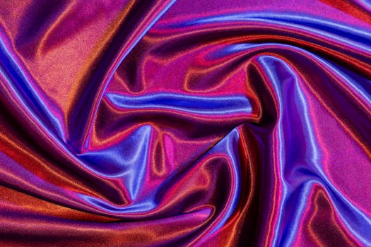 Striking abstract pattern of red and blue satin fabric with glossy folds and vibrant colors.