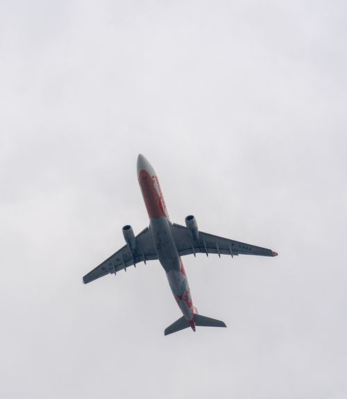 Free A low-angle view of an airplane flying overhead against a cloudy sky backdrop. Stock Photo
