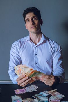 Young man in Buenos Aires counts Argentine pesos. Indoor shot with focused expression.