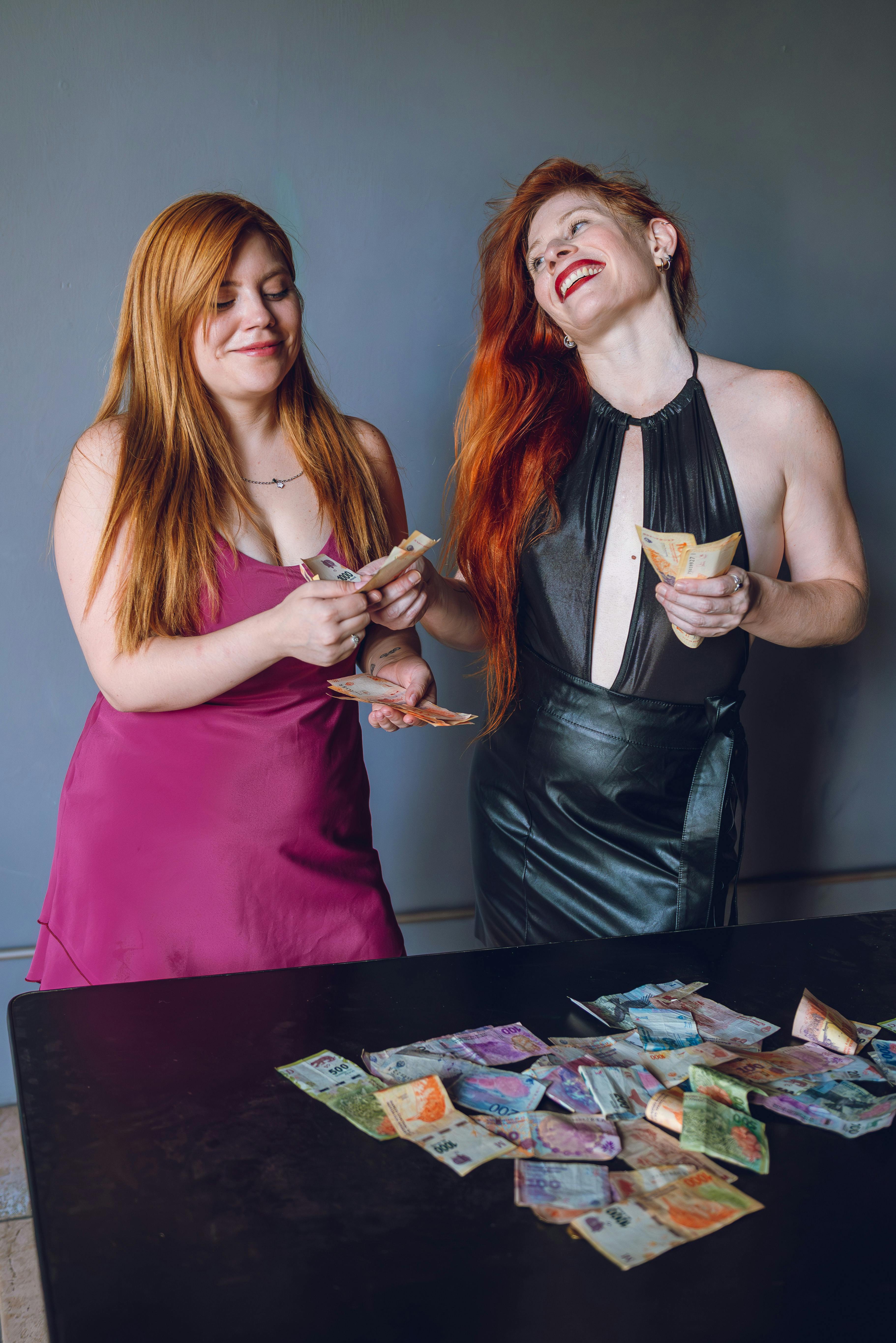 Ilmainen Kaksi naista laskee värikkäitä argentiinalaisia ​​pesoja sisätiloissa pöydässä. Kuvapankkikuva