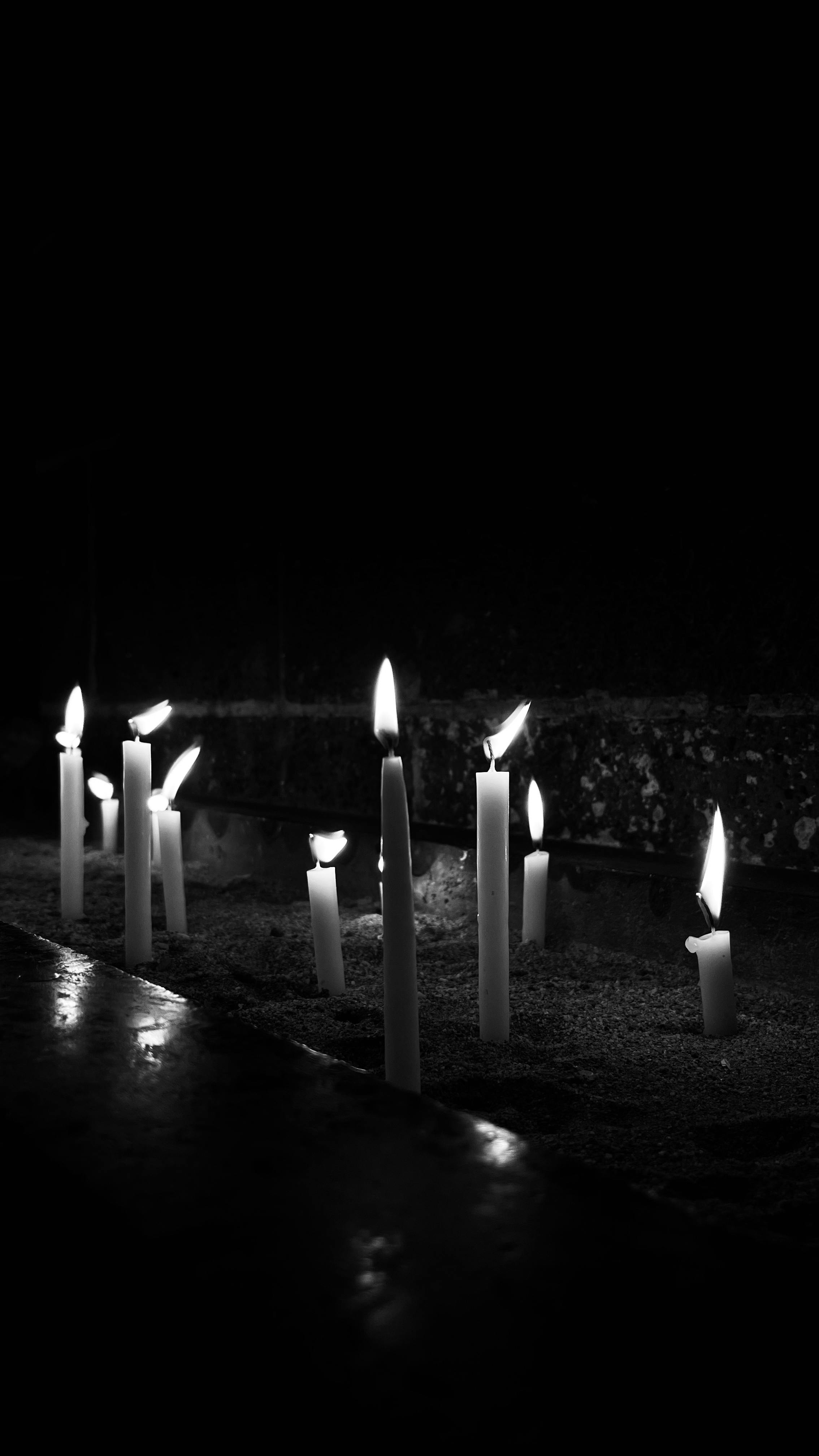 gratis Zwart-witfoto van brandende kaarsen in een schemerig verlichte ruimte, die een serene sfeer creëren. Stockfoto