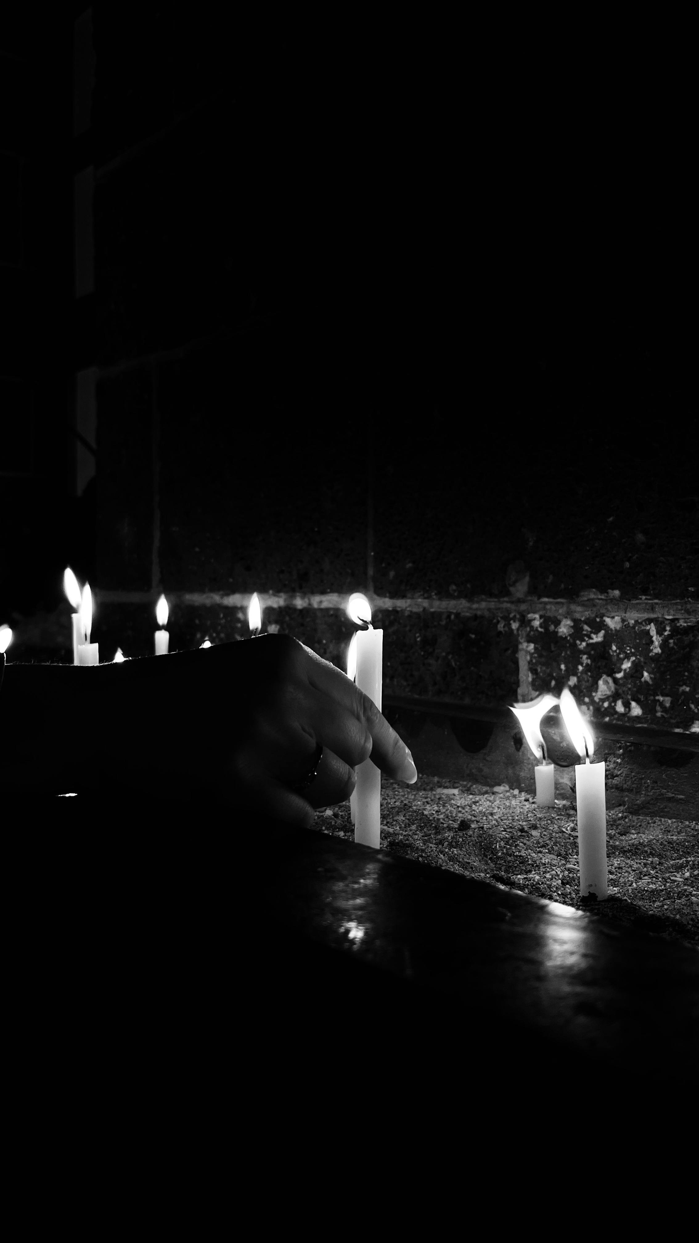 bezplatná Černobílá fotografie ruky zapalující svíčky během slavnostní vigilie. Základová fotografie