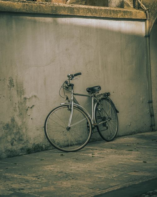 Free A classic bicycle leaning against a worn, textured wall, evoking nostalgia. Stock Photo