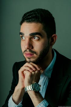 一位穿着时尚服装、戴着手表、抬头仰望的男人的肖像，他显得深思熟虑