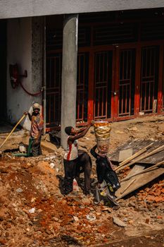 A group of construction workers engaged in manual labor on a city building site.