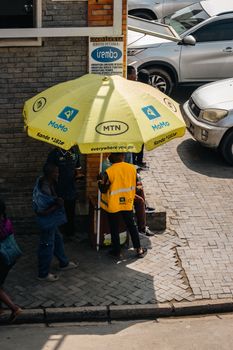 Street vendor in Ghana under MTN yellow umbrella representing MTN MoMo mobile money