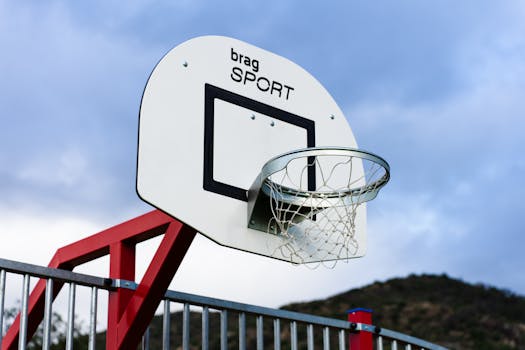 Close-up of a basketball hoop with red support in an outdoor setting.