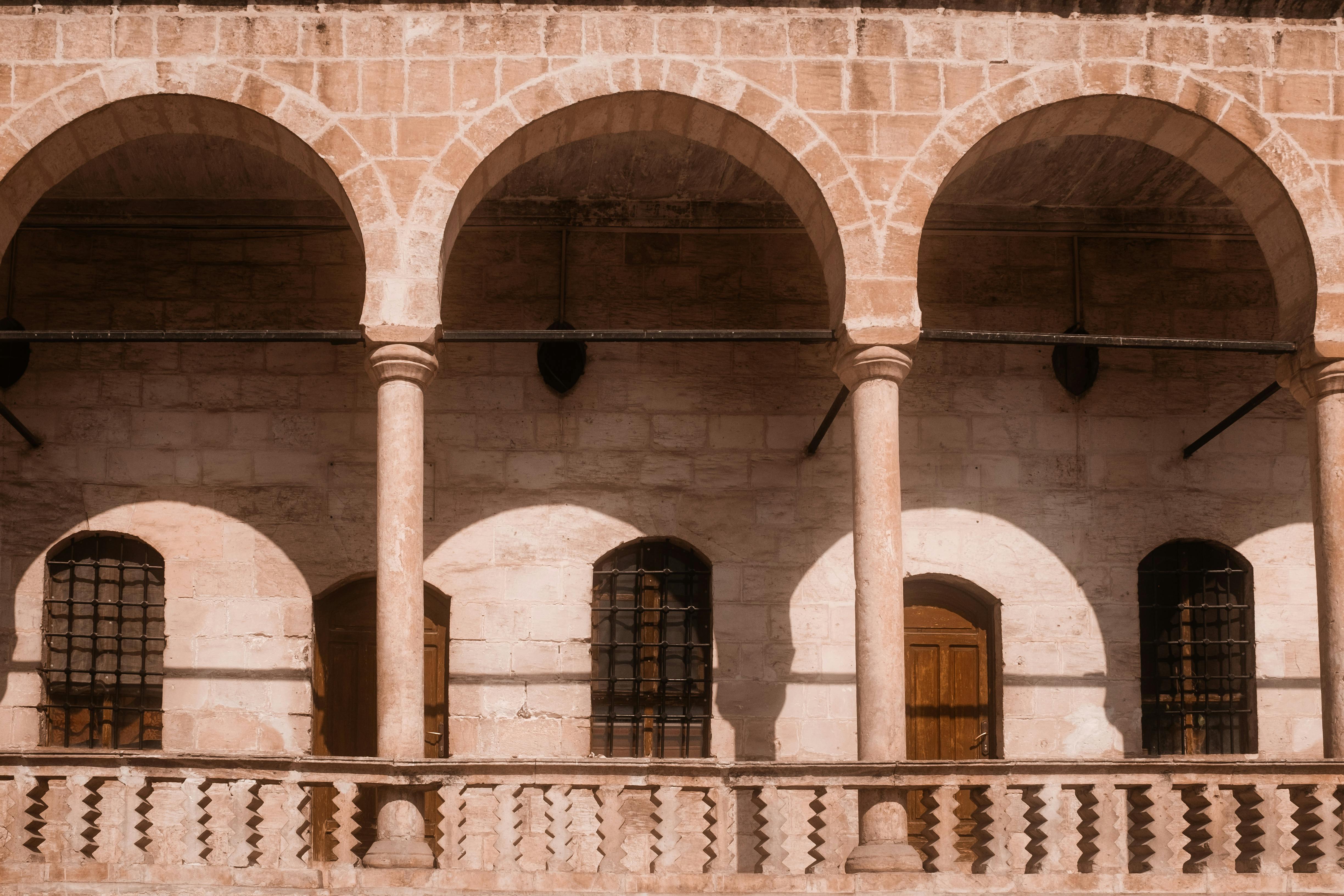 Gratis Un'immagine accattivante di archi storici che proiettano ombre in una luce calda e soffusa, mettendo in mostra la bellezza architettonica classica. Foto a disposizione