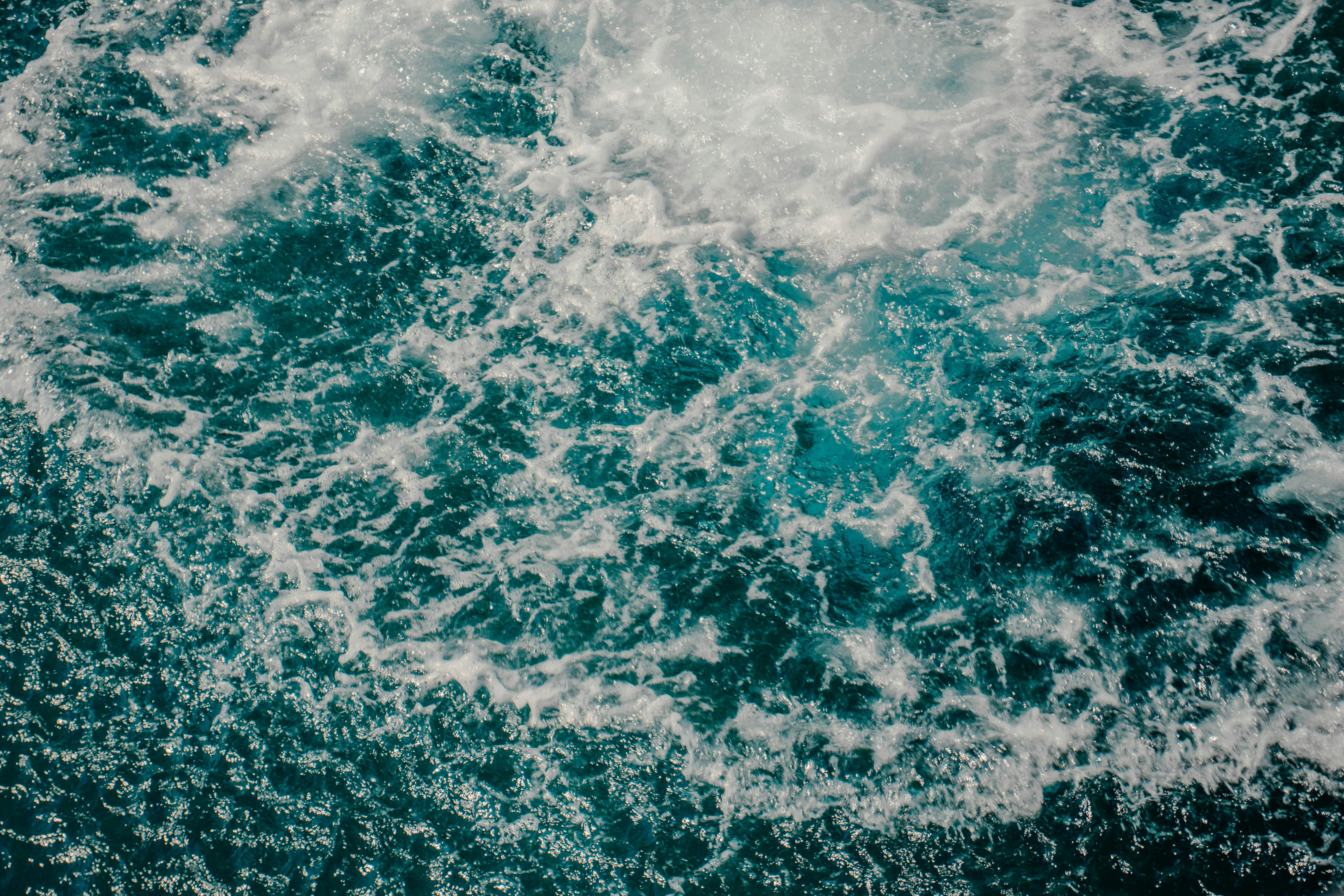 Free Vibrant aerial view of ocean waves creating intricate patterns in a turquoise sea, capturing motion and energy. Stock Photo