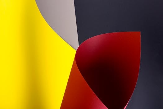 Vibrant abstract image featuring curved sheets of yellow, red, gray, and dark paper.