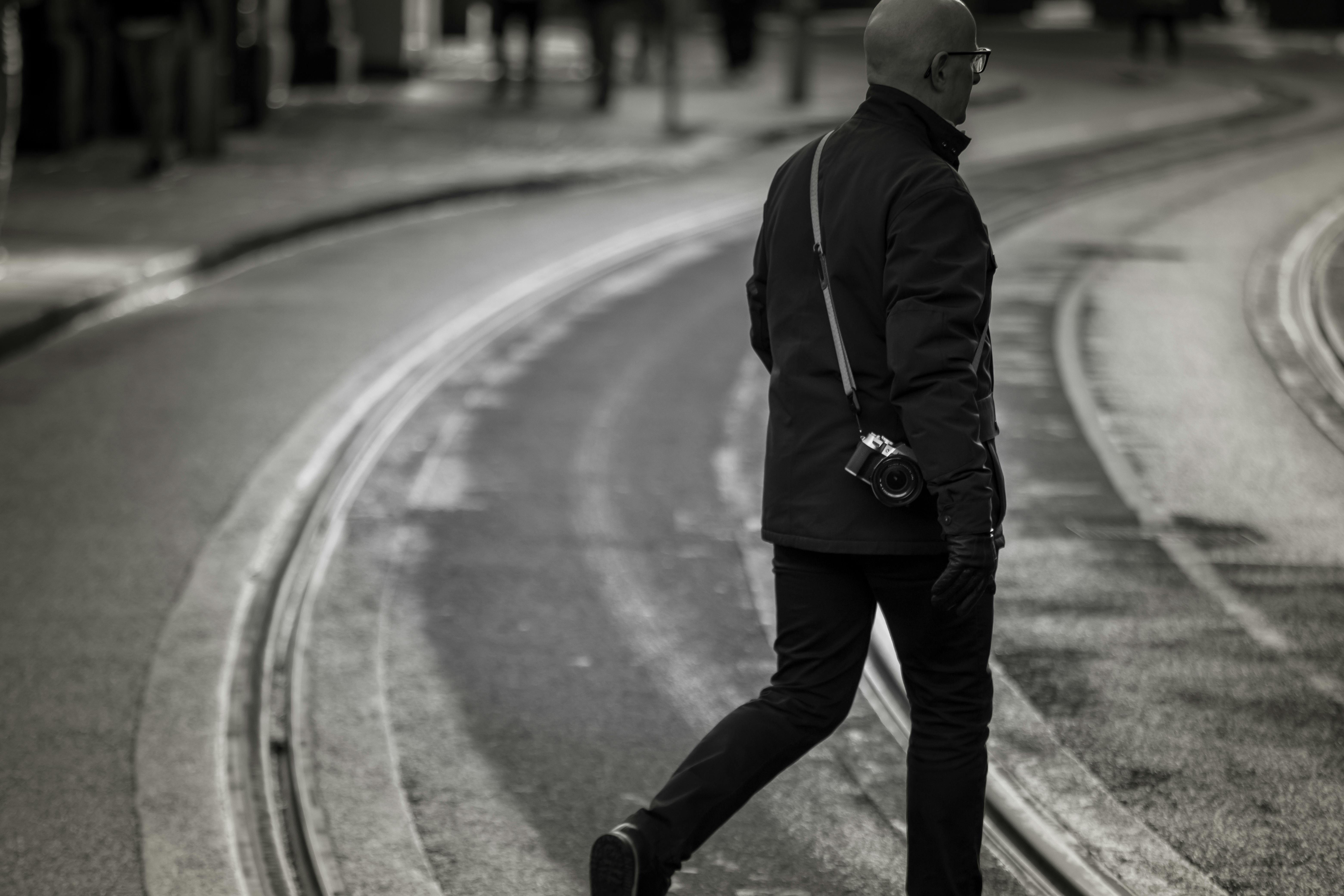 Miễn phí Một người đàn ông cầm máy ảnh đi dọc theo đường ray xe điện ở hạt Dublin, Ireland, ghi lại cuộc sống thành phố. Ảnh lưu trữ