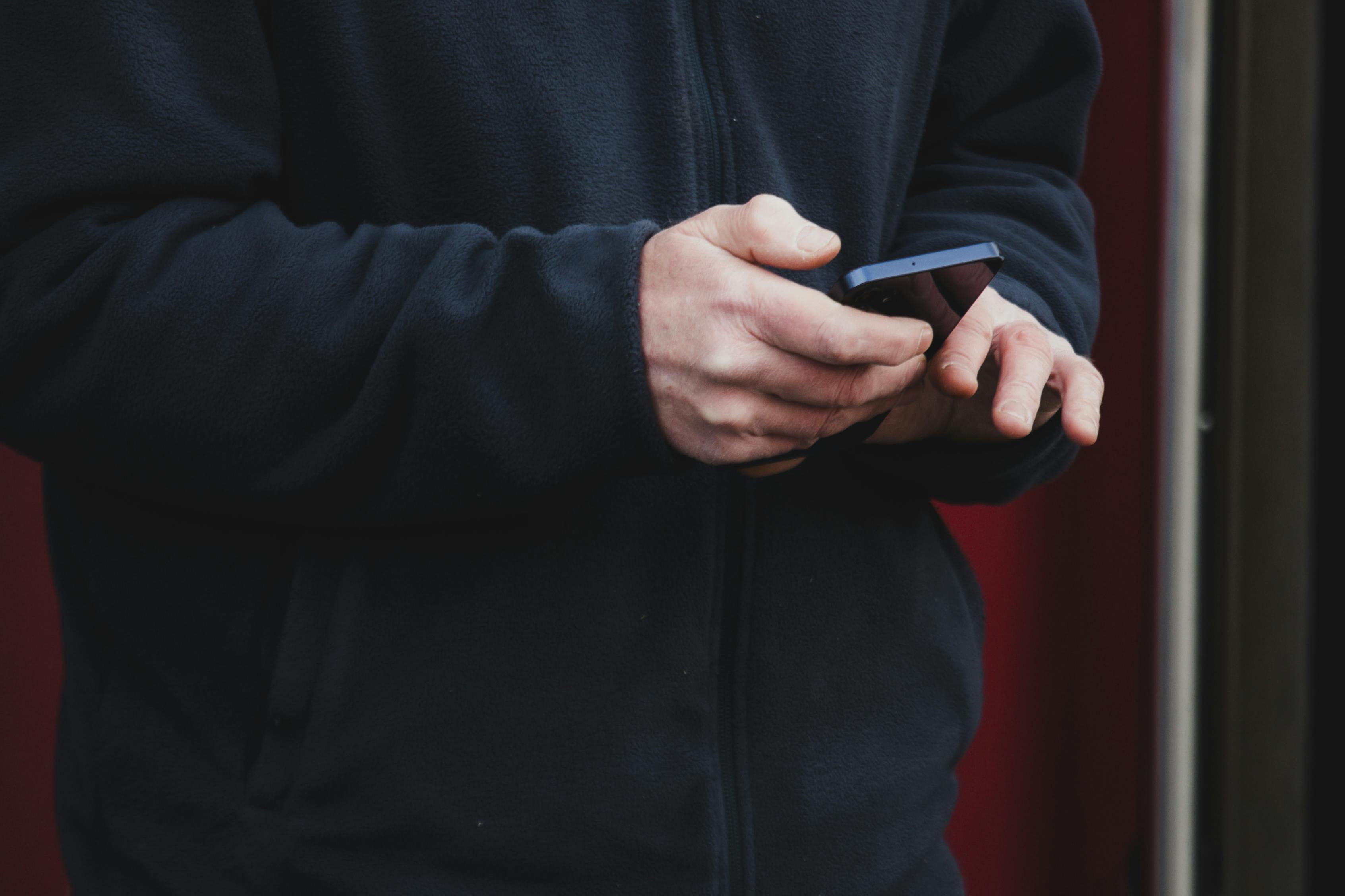 Gratuit Gros plan sur une personne en train d'envoyer des SMS sur son smartphone à l'extérieur, à Dublin, portant une veste bleu marine. Photos