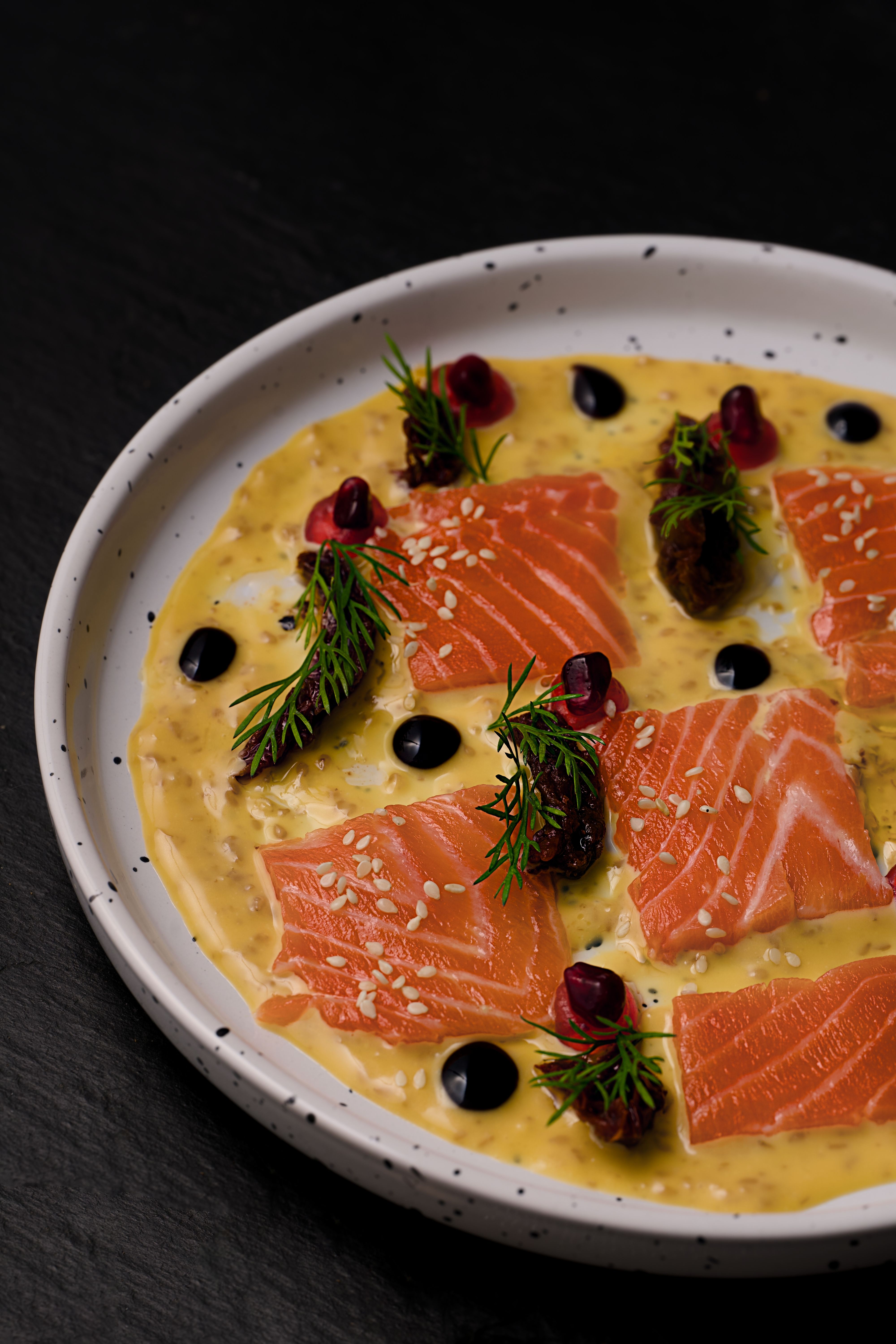 Fresh salmon tartare served with pomegranate and herbs on a ceramic plate.