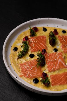 Fresh salmon tartare served with pomegranate and herbs on a ceramic plate.