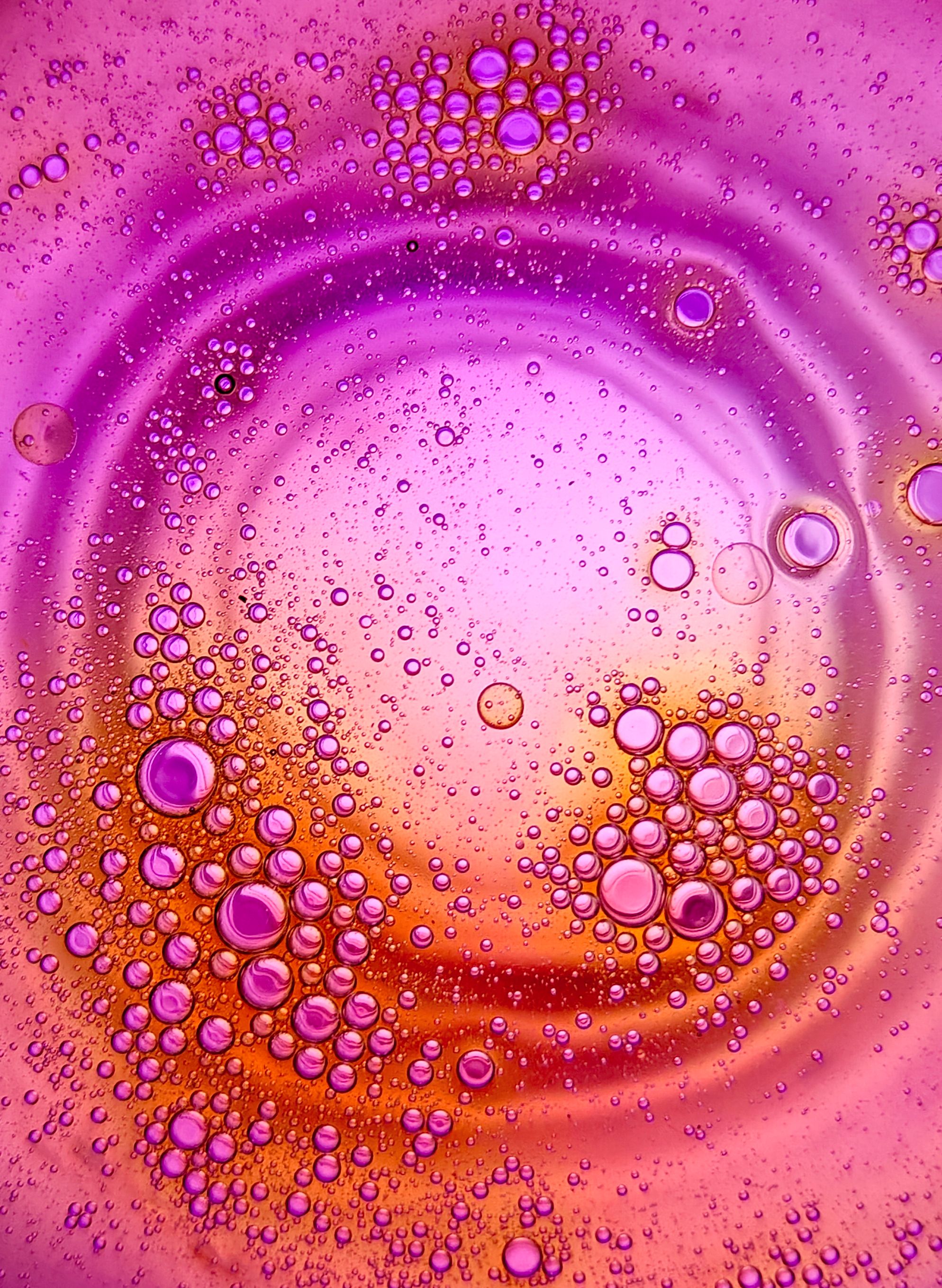 Free Abstract oil bubbles in water creating a vibrant purple and orange artistic pattern. Stock Photo