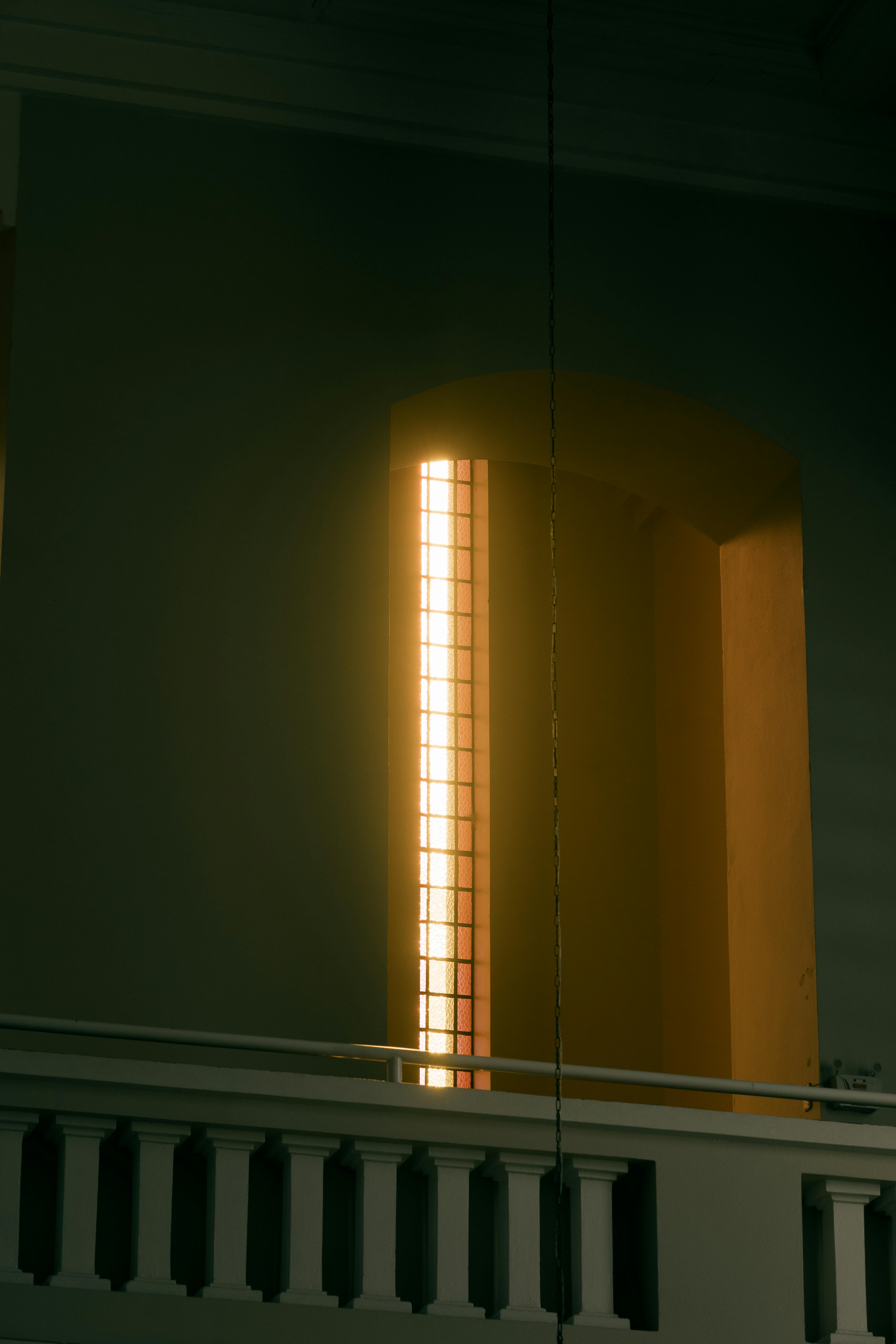 Free Soft sunlight streams through a stained glass window inside a church, casting a peaceful glow. Stock Photo