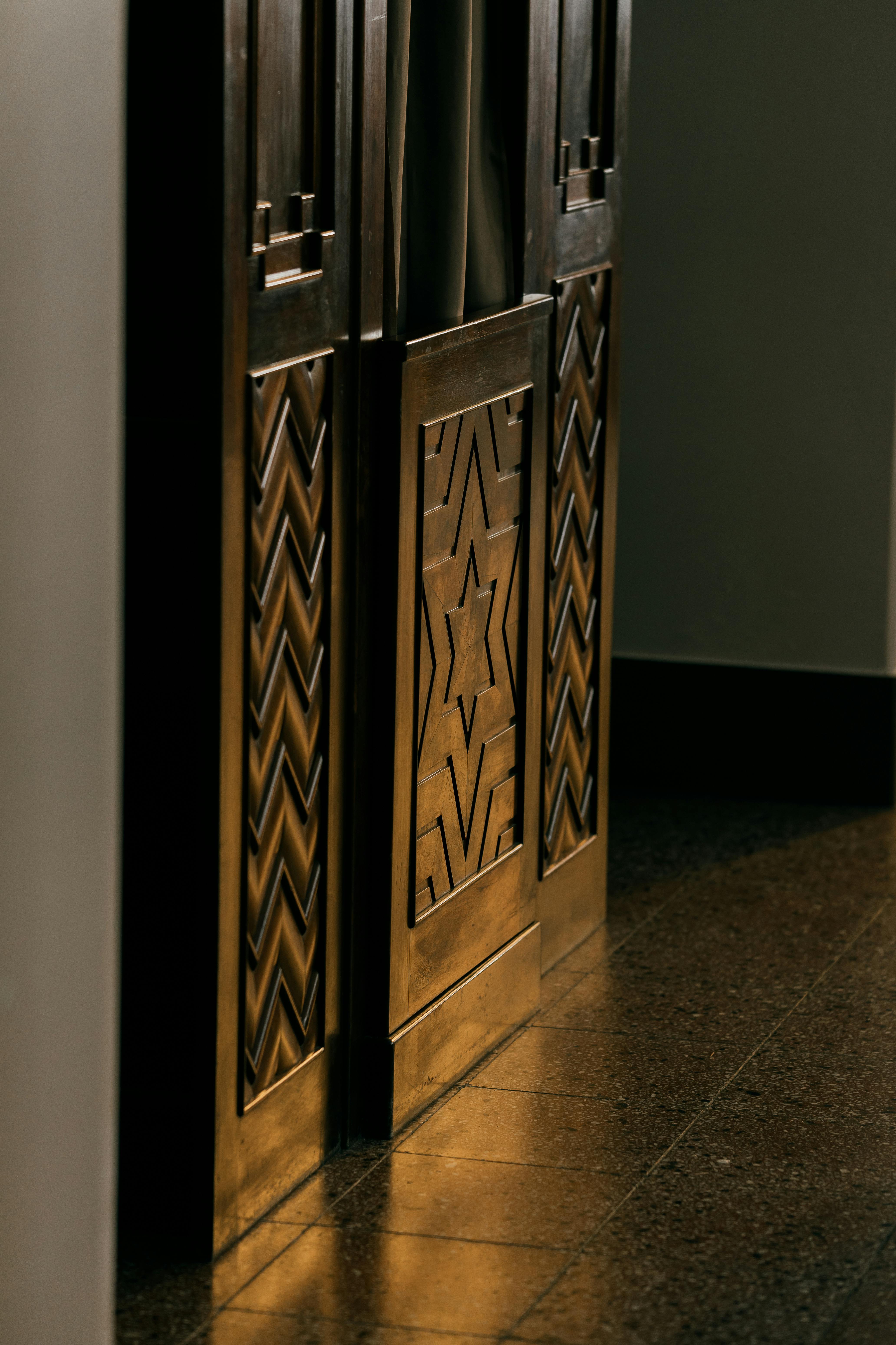 ingyenes Művészi fotó egy faajtóról, bonyolult geometriai mintákkal és napfény-visszaverődésekkel. Stockfotó