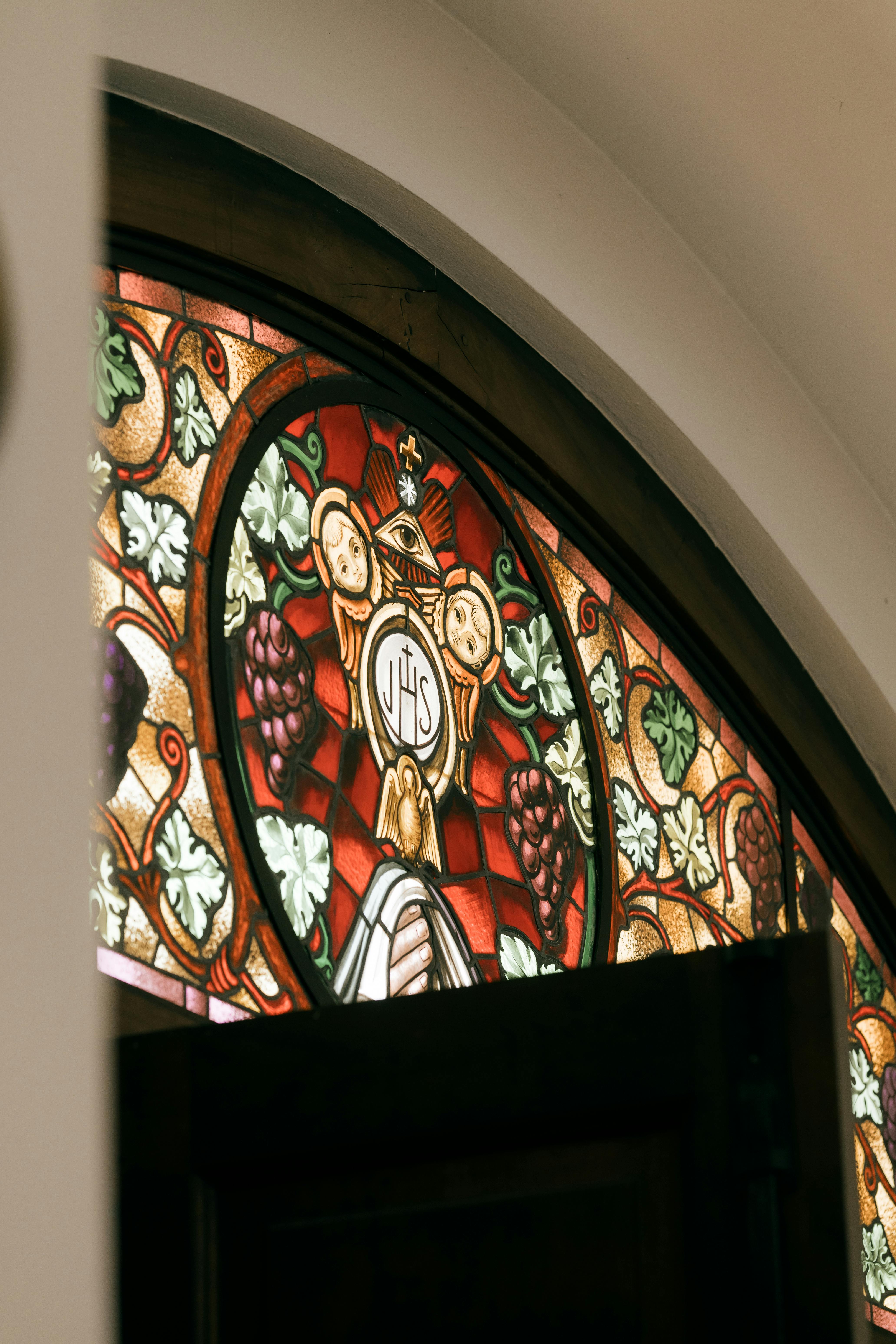 Free Close-up of a colorful stained glass window with intricate religious symbols. Stock Photo