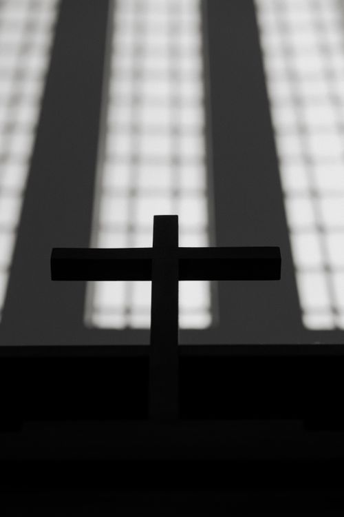 Free Silhouette of church cross against blurred window background, creating a dramatic effect. Stock Photo