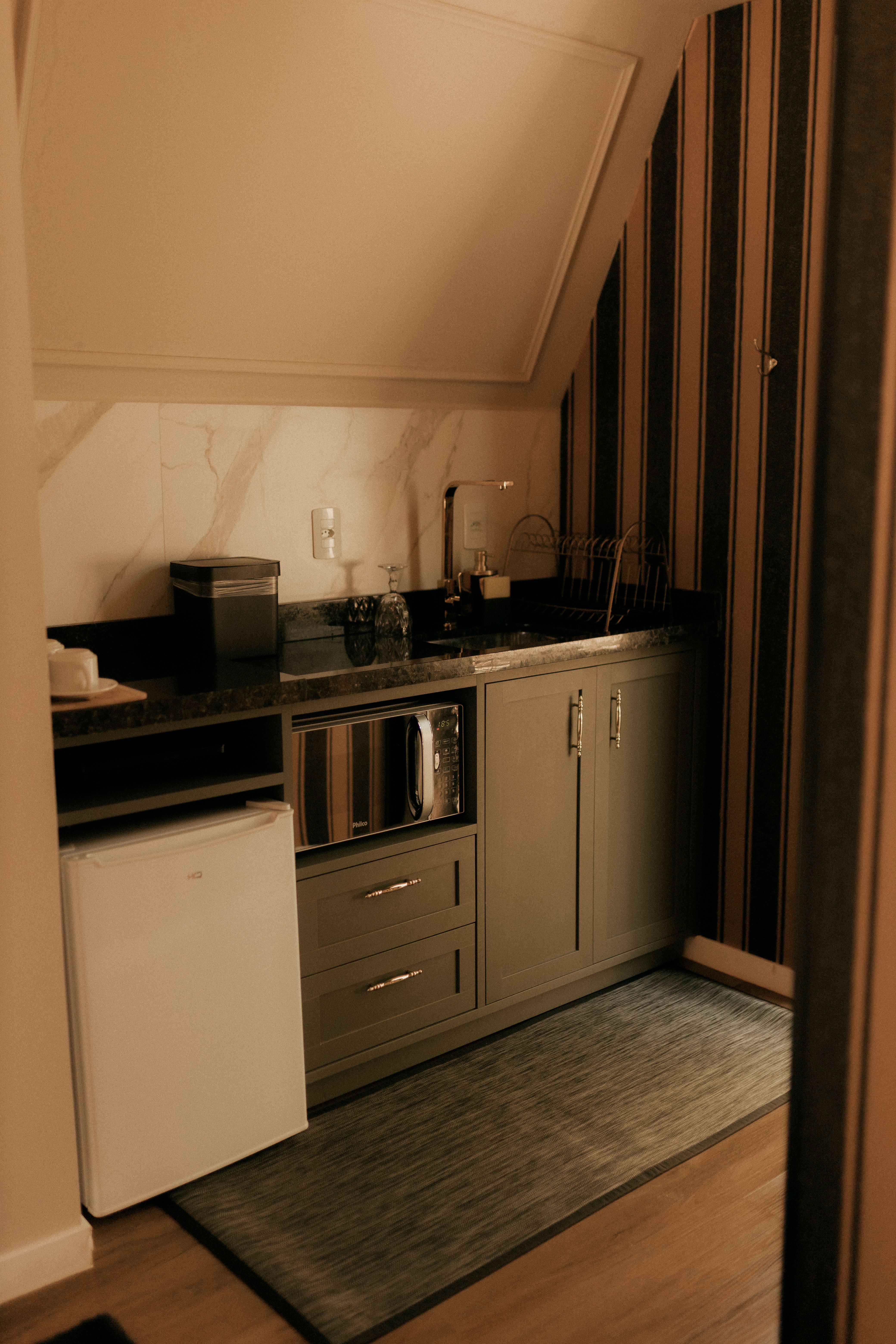 stainless steel undercounter mini fridge next to a kitchen coffee bar