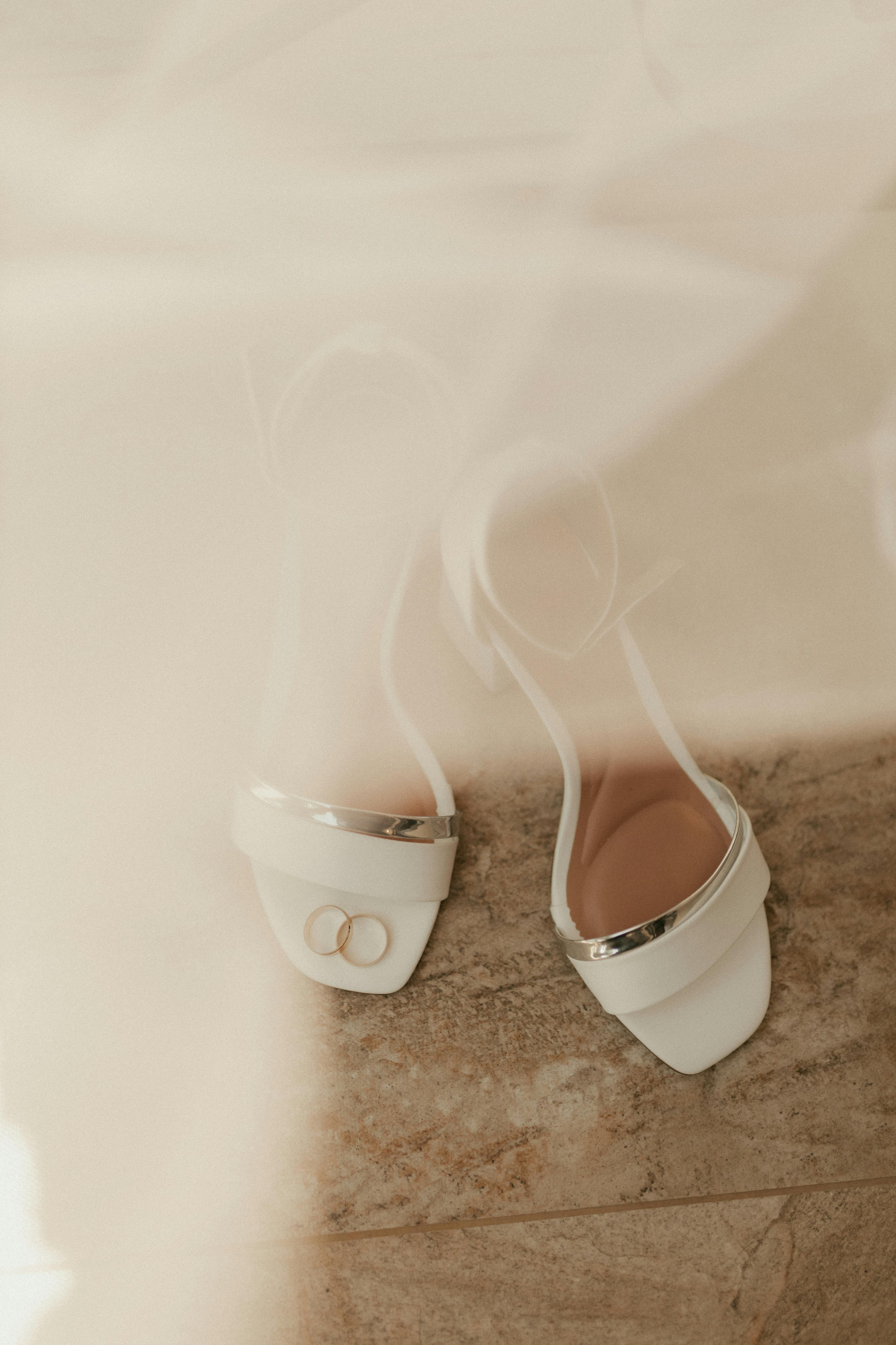Free Stylish bridal shoes with wedding rings elegantly placed, embodying romance and commitment. Stock Photo