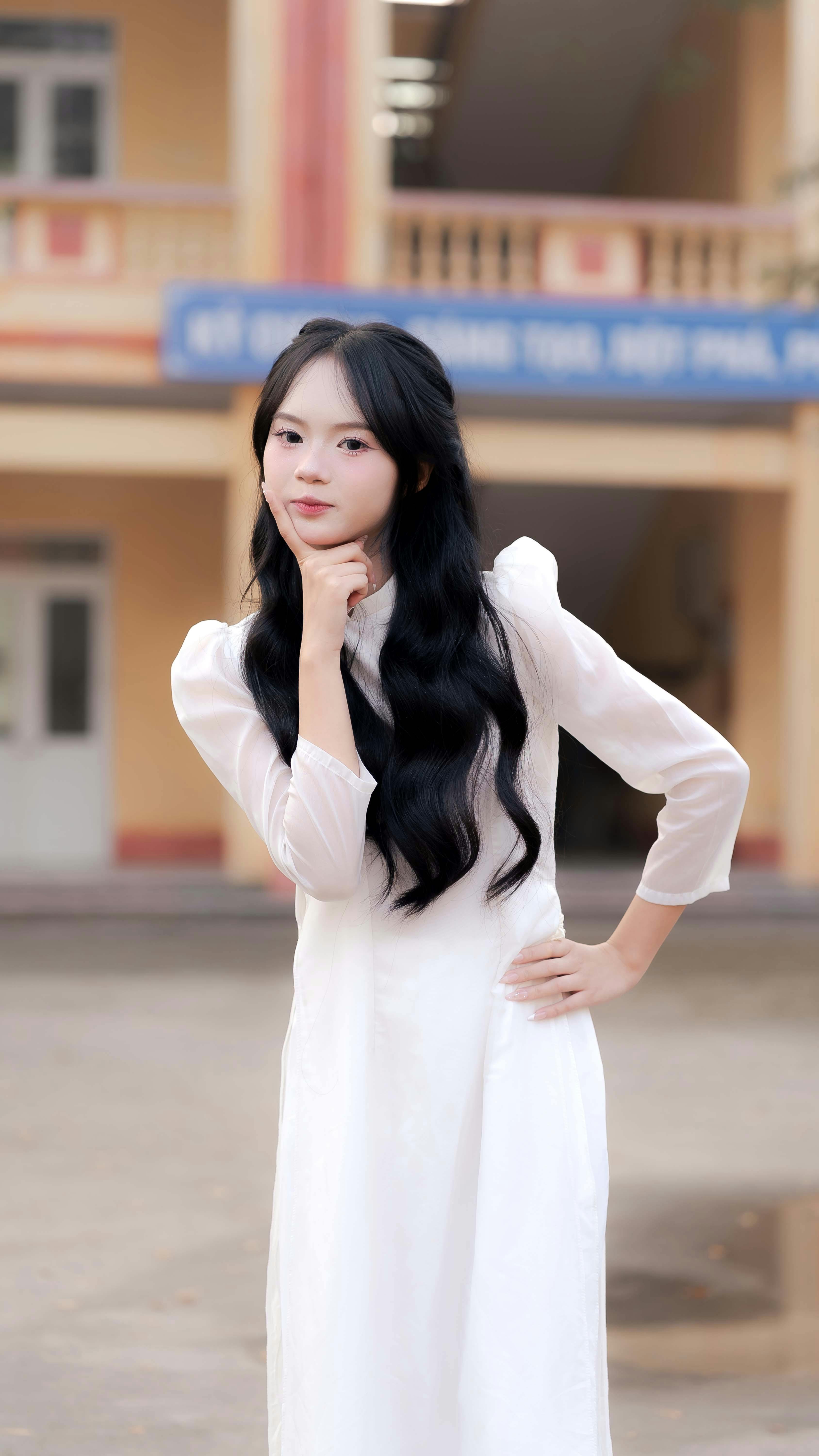 Free A young woman wearing a traditional white dress poses confidently in an outdoor setting. Stock Photo