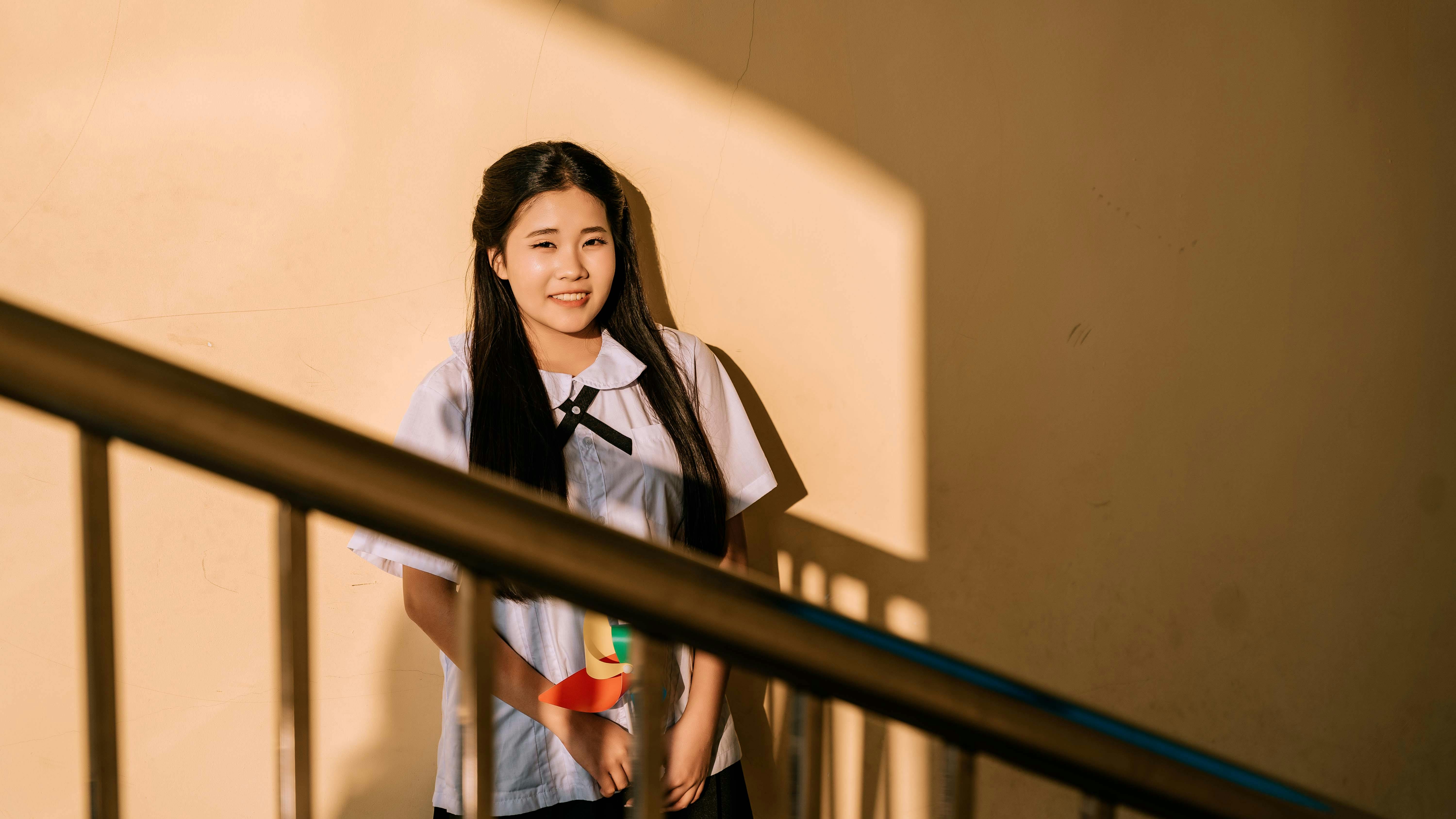 bezplatná Žena ve školní uniformě stojící u zdi v teplém slunečním světle. Základová fotografie