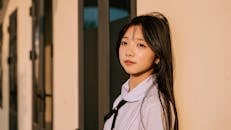 Young Woman Leaning Against Building in Sunlight
