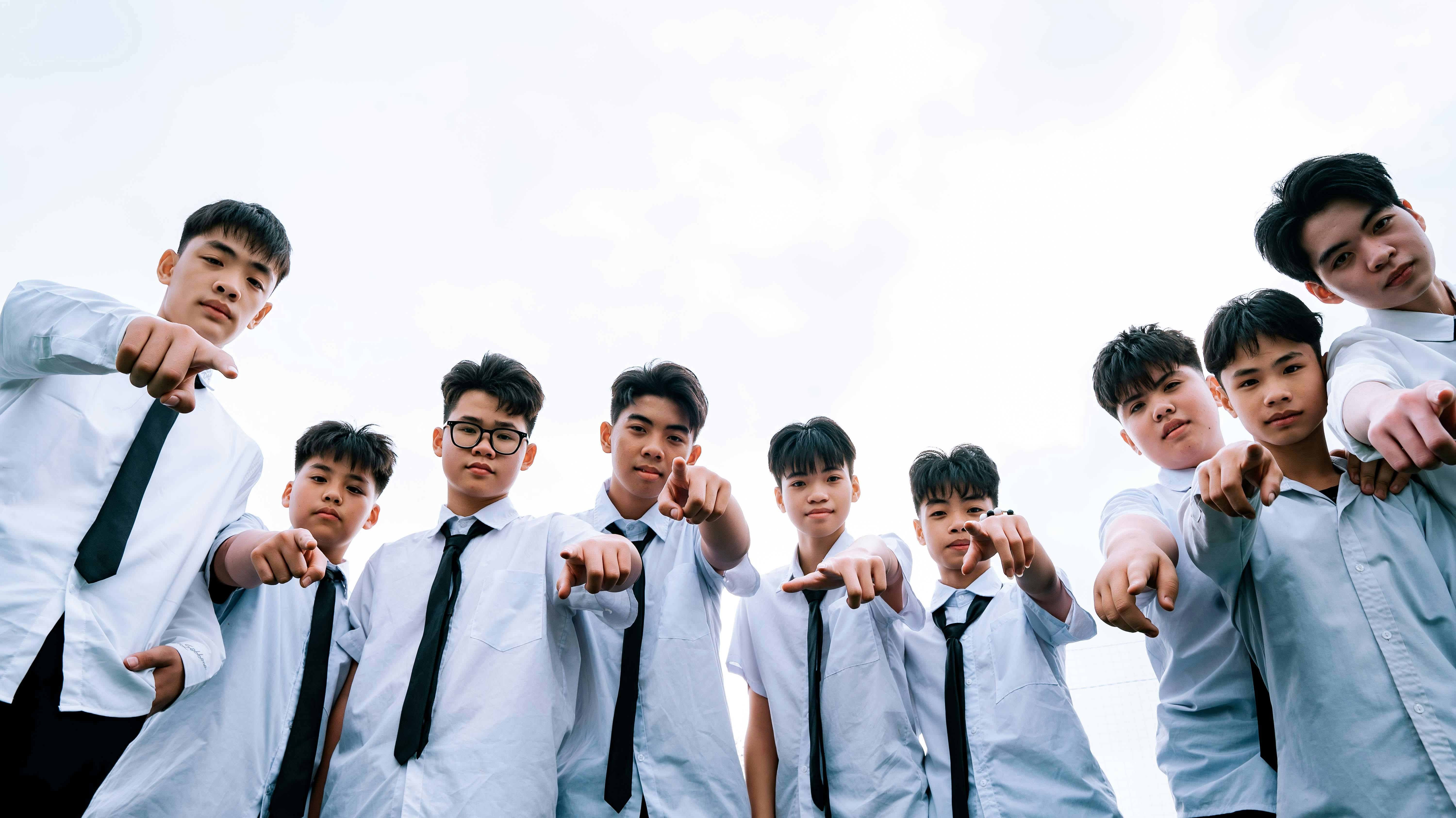 Δωρεάν Μια ομάδα εφήβων με στολές που δείχνουν προς τα πάνω με φόντο έναν καθαρό ουρανό. Φωτογραφία από στοκ φωτογραφιών