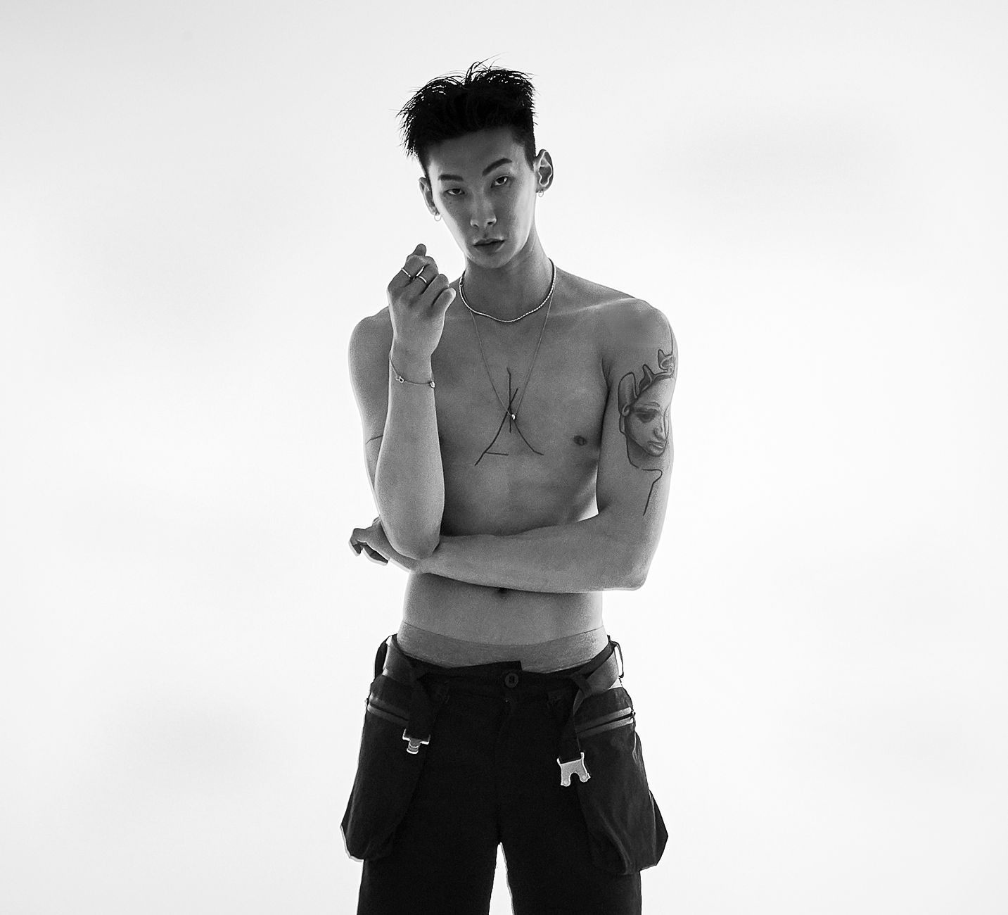 Black and white portrait of a tattooed man showcasing modern style and masculine fashion.
