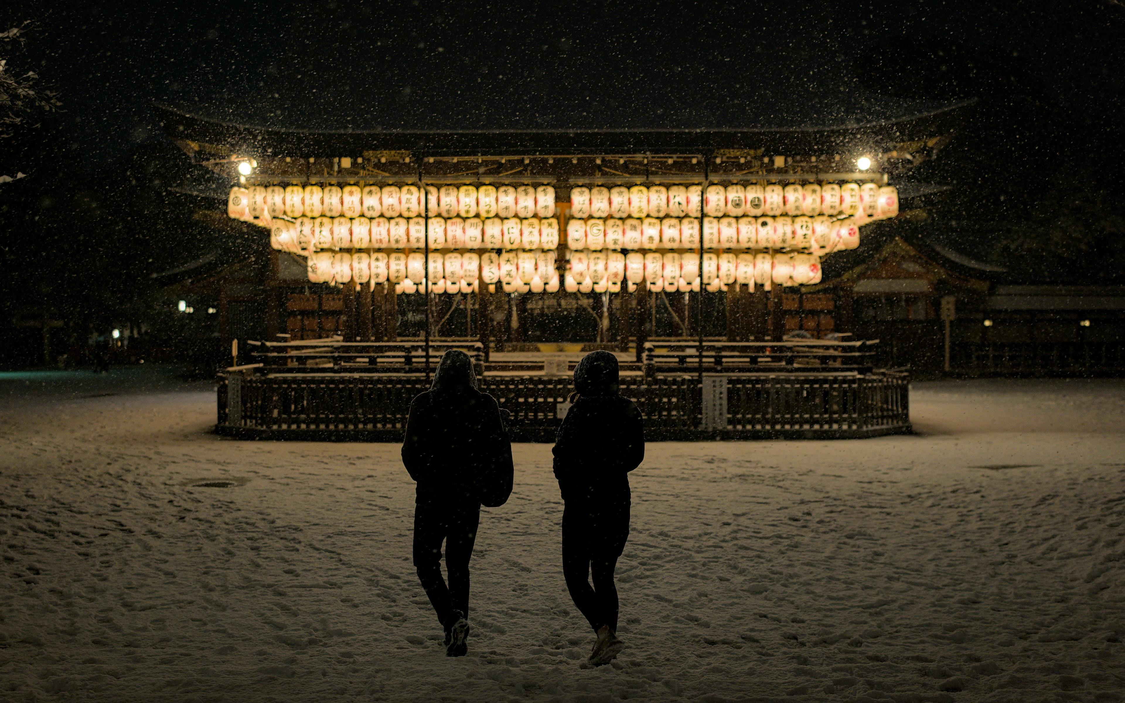 Kostenlos Ein Paar spaziert nachts im Schnee unter Laternen am Yasaka-Schrein in Kyoto. Stock-Foto